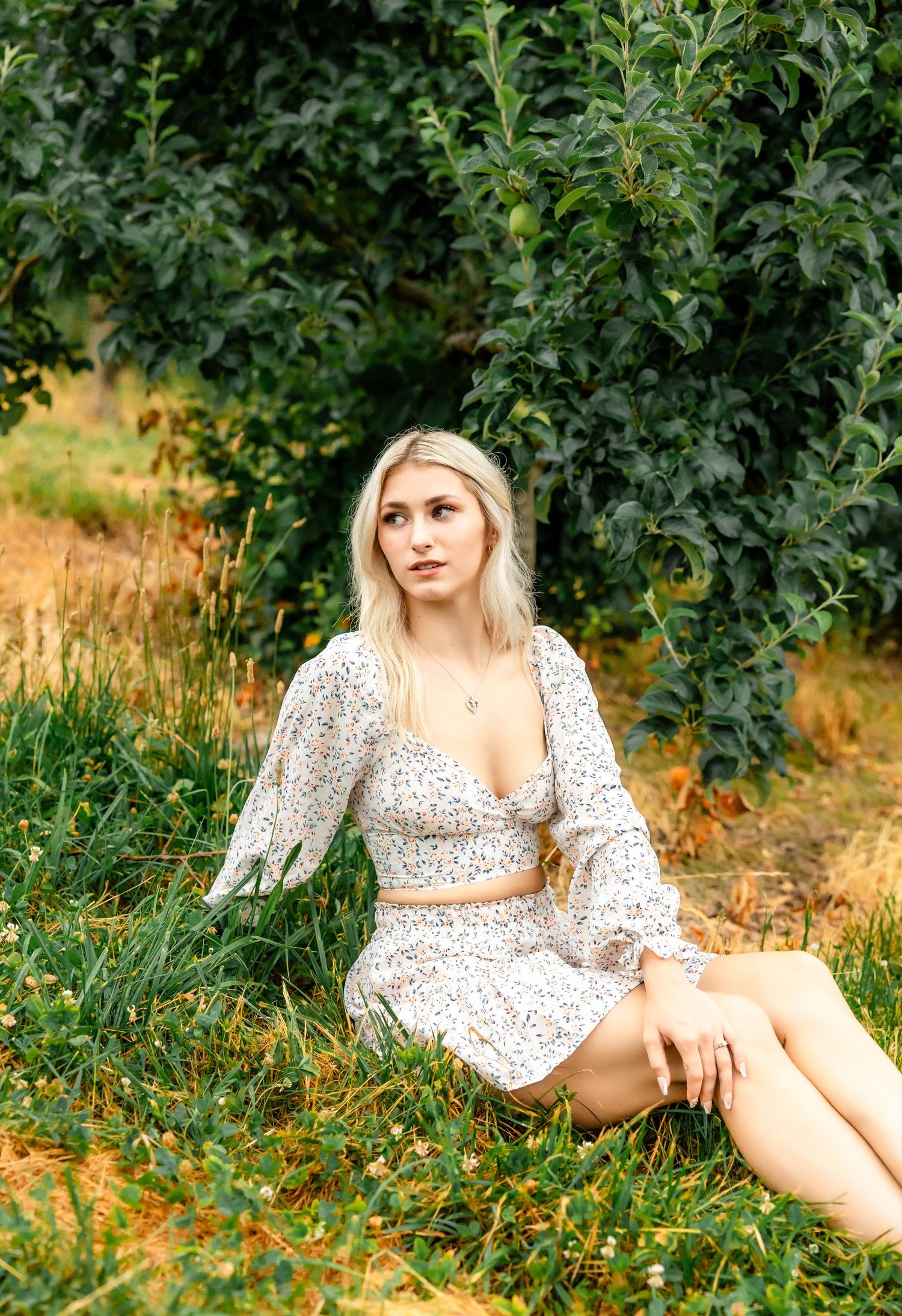 Dreamy outdoor fashion photography featuring a white floral two-piece dress in an orchard setting.