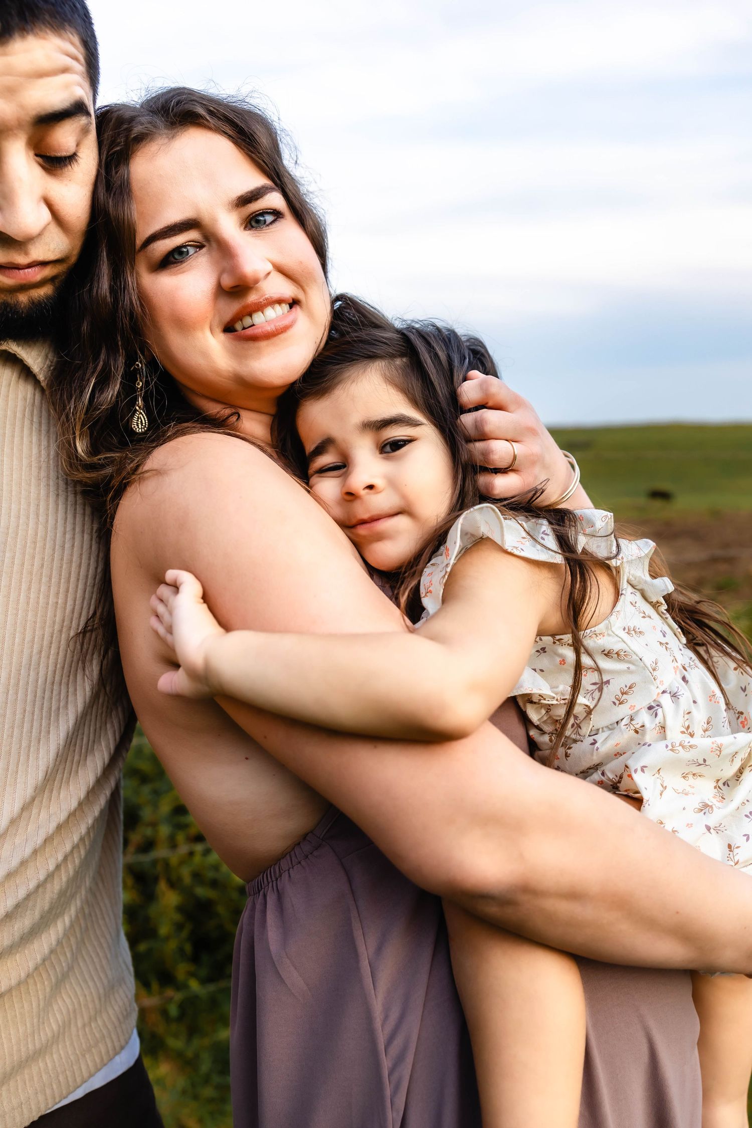 Close up of family sharing warm embrace outdoors against pastoral backdrop.