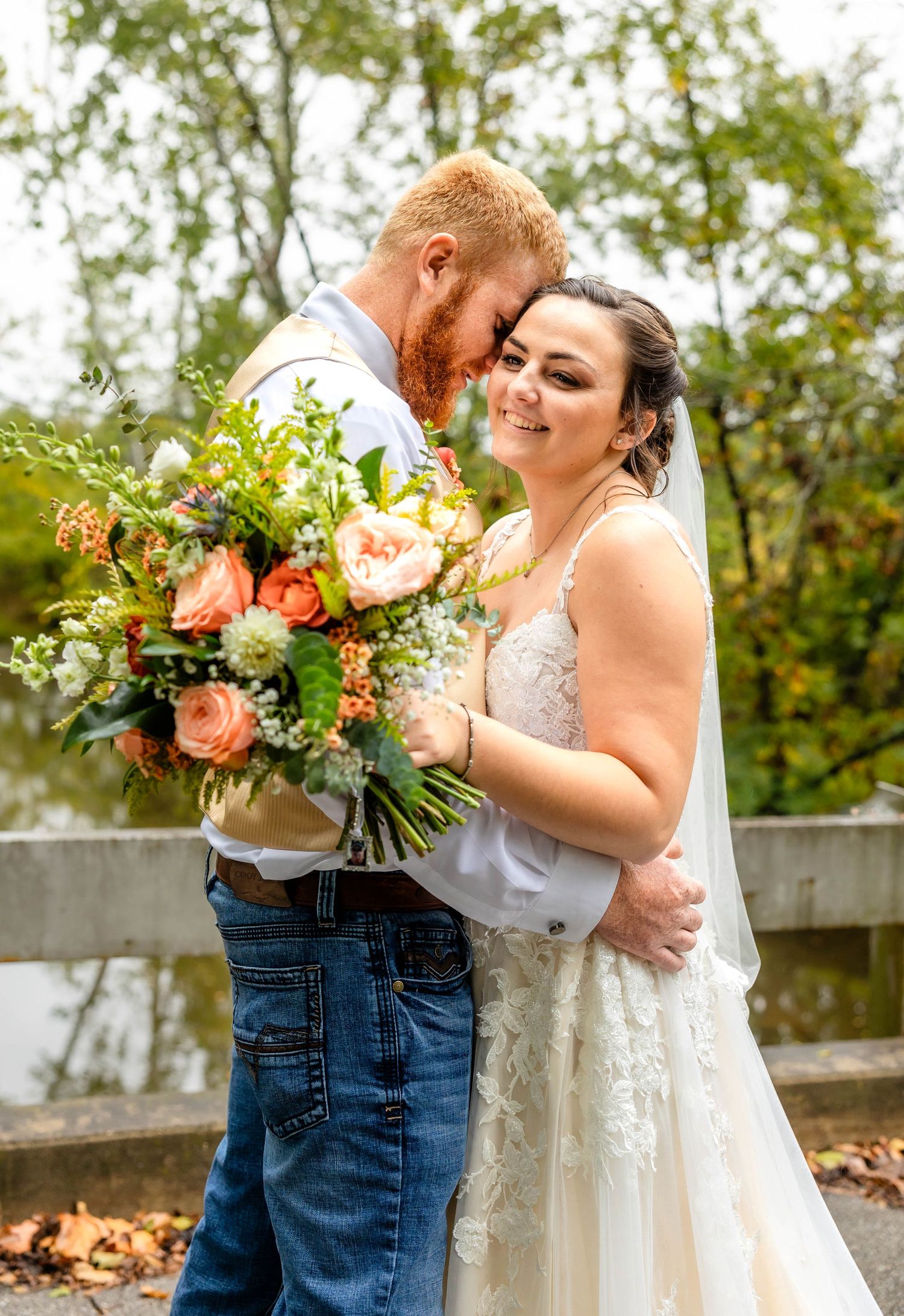 A tender wedding moment captured with a beautiful coral and peach floral bouquet.