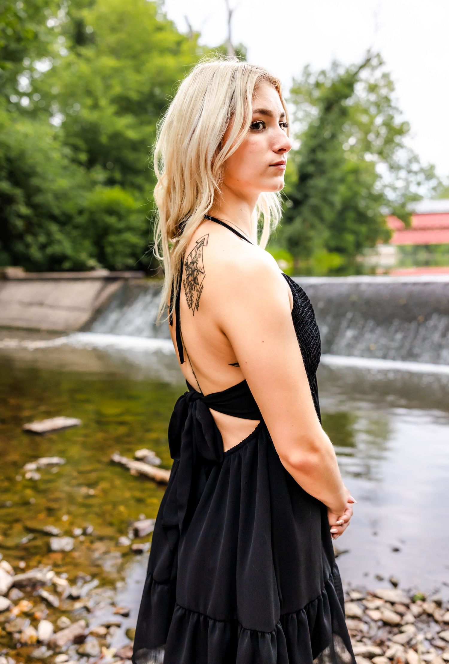 A black summer dress photographed against a waterfall backdrop in a natural outdoor setting.