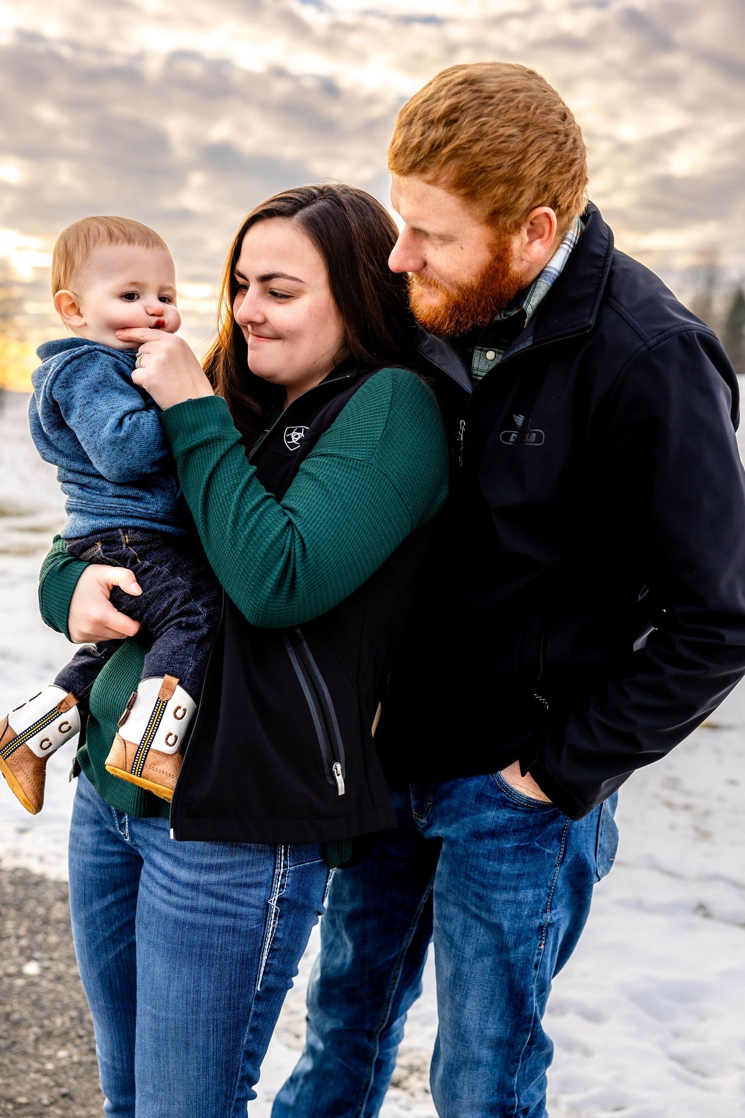 A joyful family moment captured outdoors with dramatic winter sky and snowy landscape.
