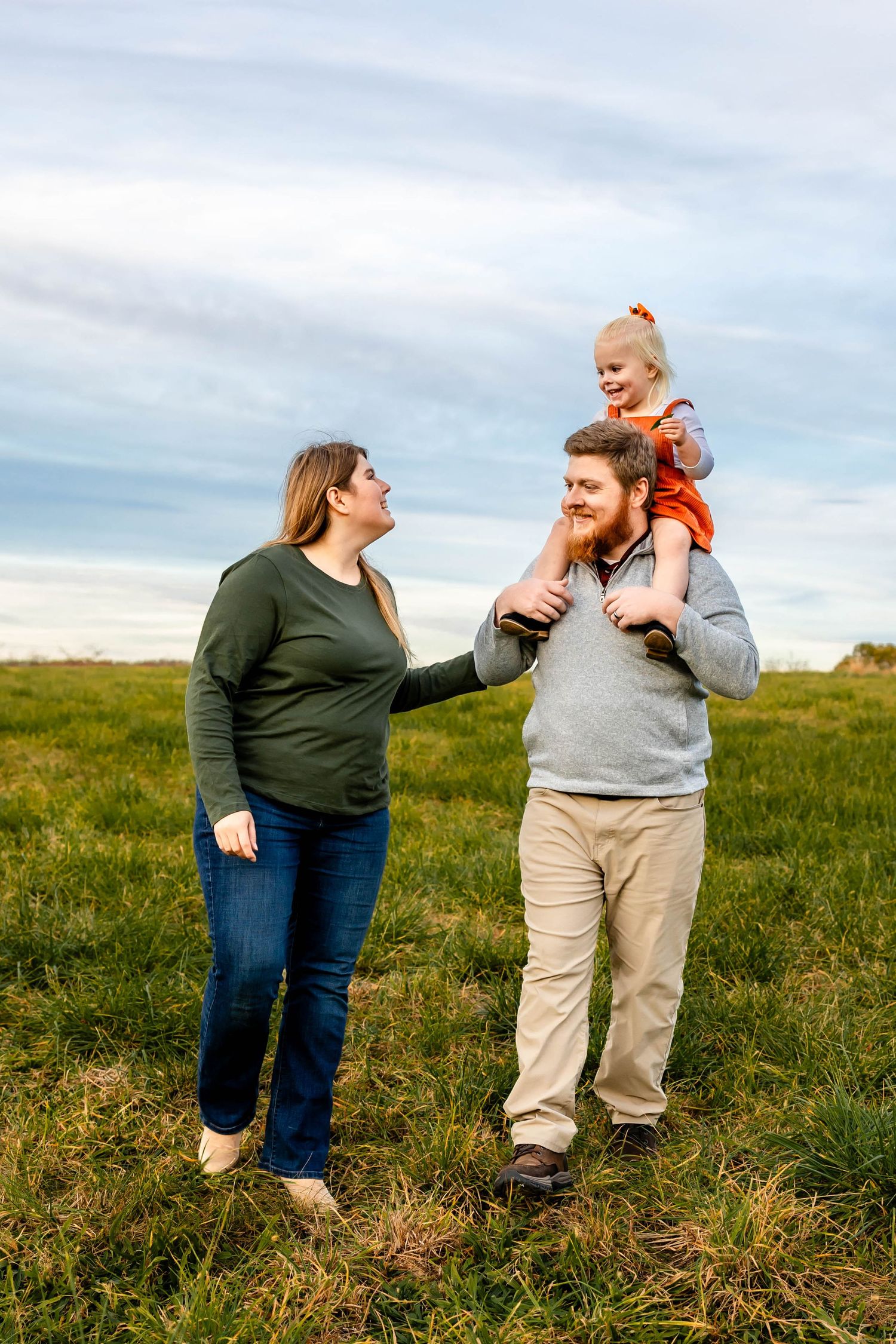 A family enjoys an autumn day together in a grassy field under blue skies.
