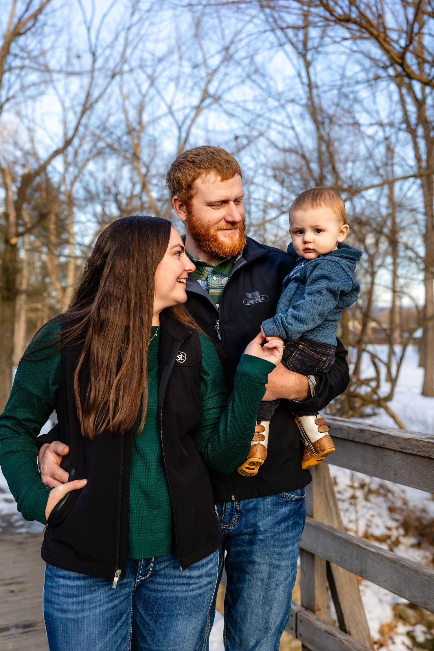 Candid family moment captured on wooden bridge during winter afternoon.
