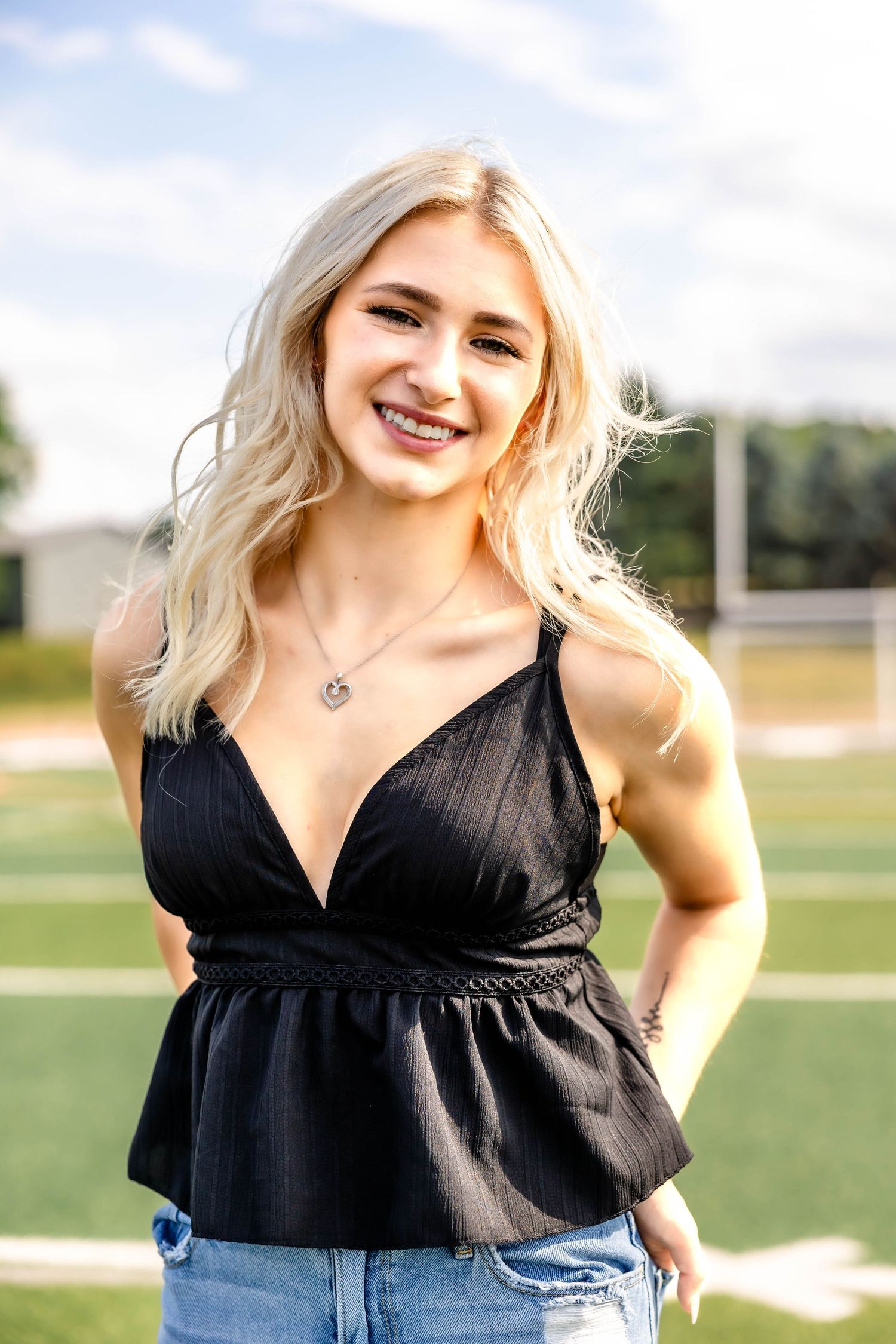 Trendy summer outfit with black v-neck peplum top and ripped jeans photographed outdoors.