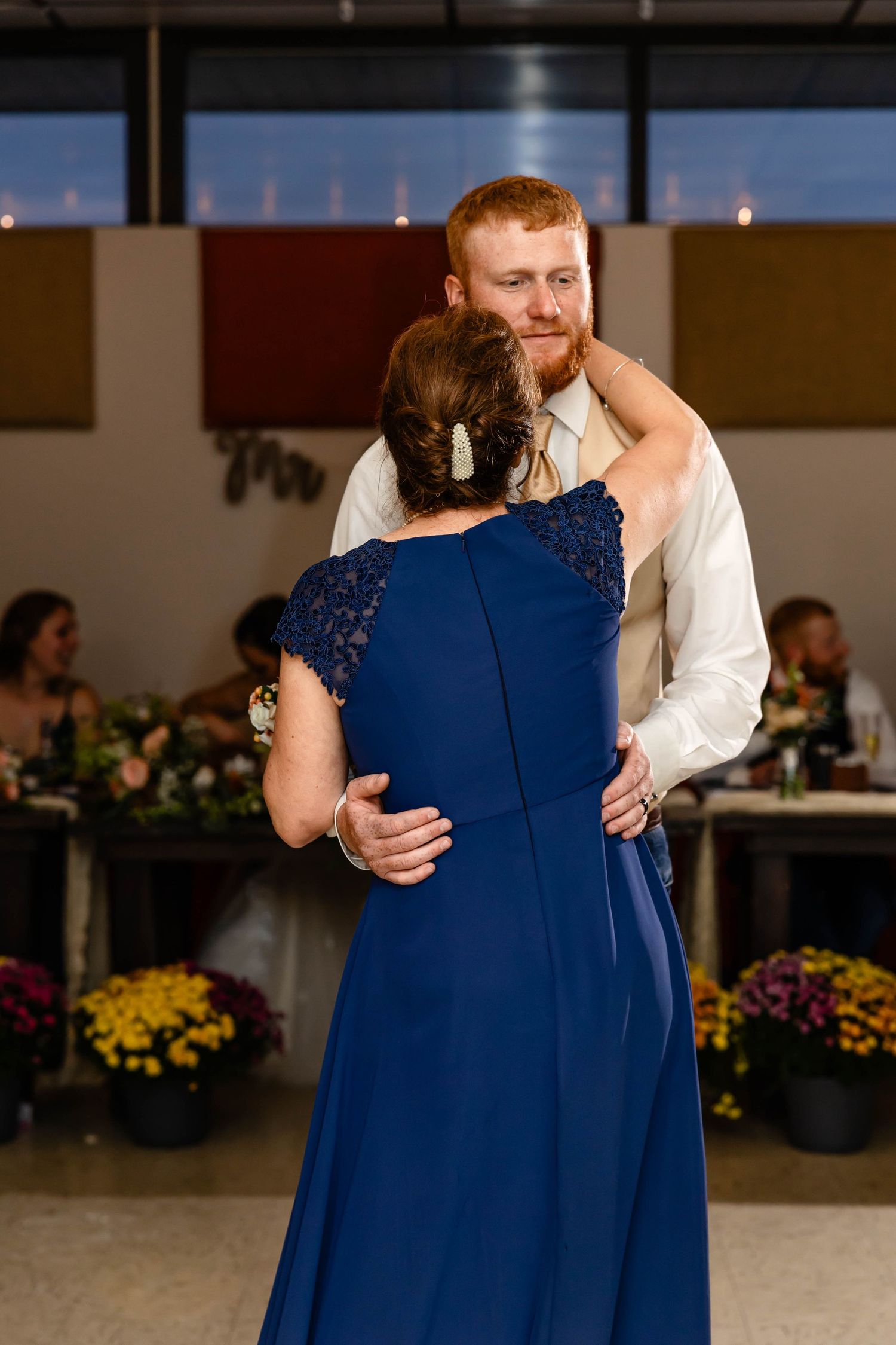 A couple shares a romantic dance at their wedding reception with yellow flowers in the background.