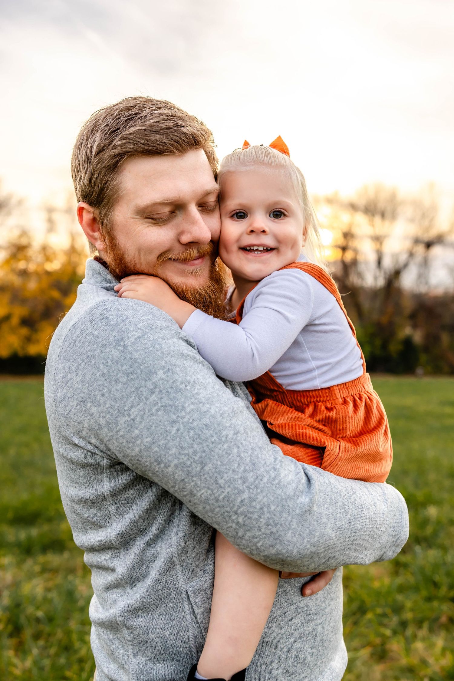 Heartwarming candid moment between parent and child sharing laughter in an autumn field.