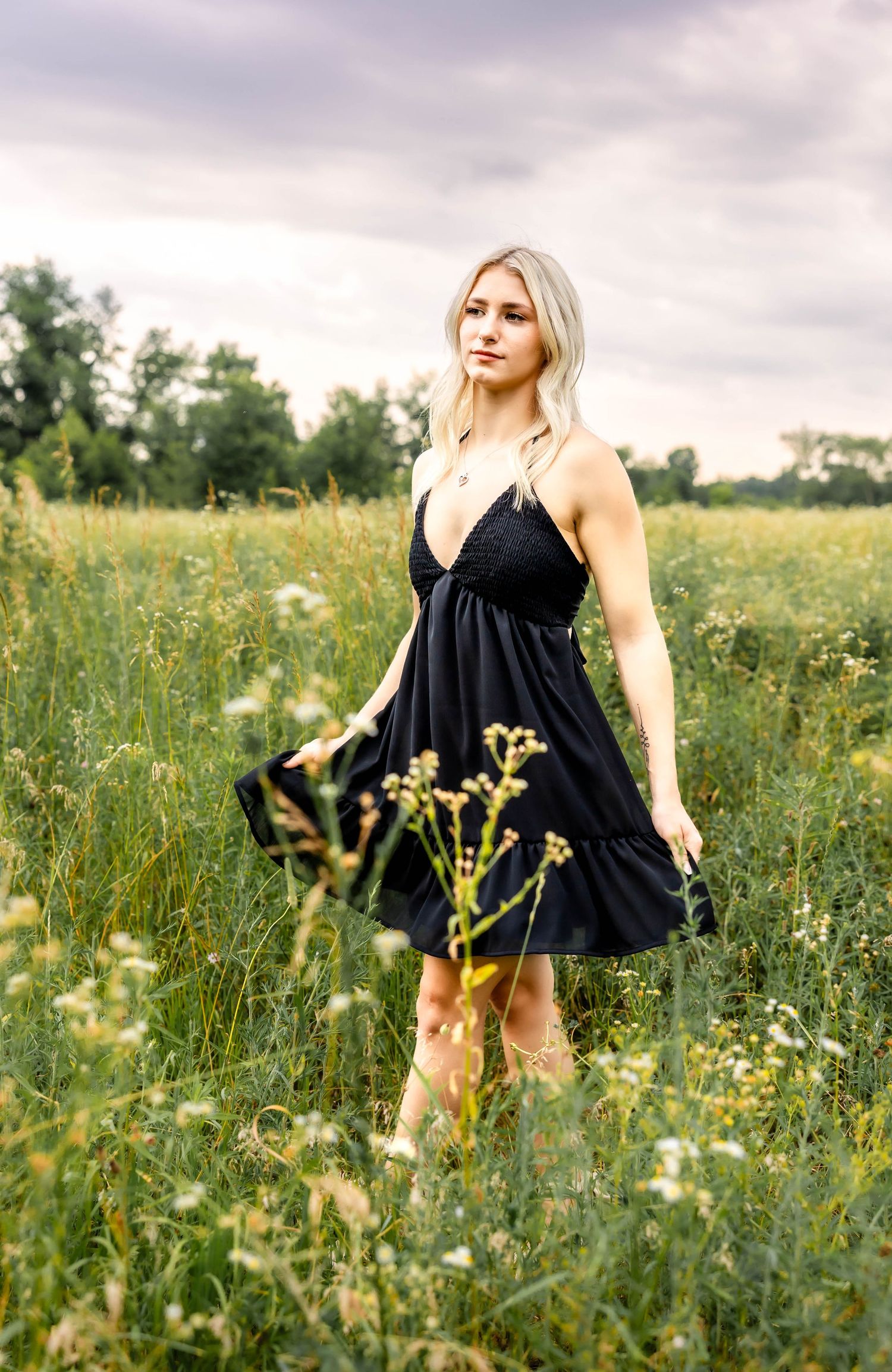 Black spaghetti strap dress captured in motion among tall grass and wildflowers.