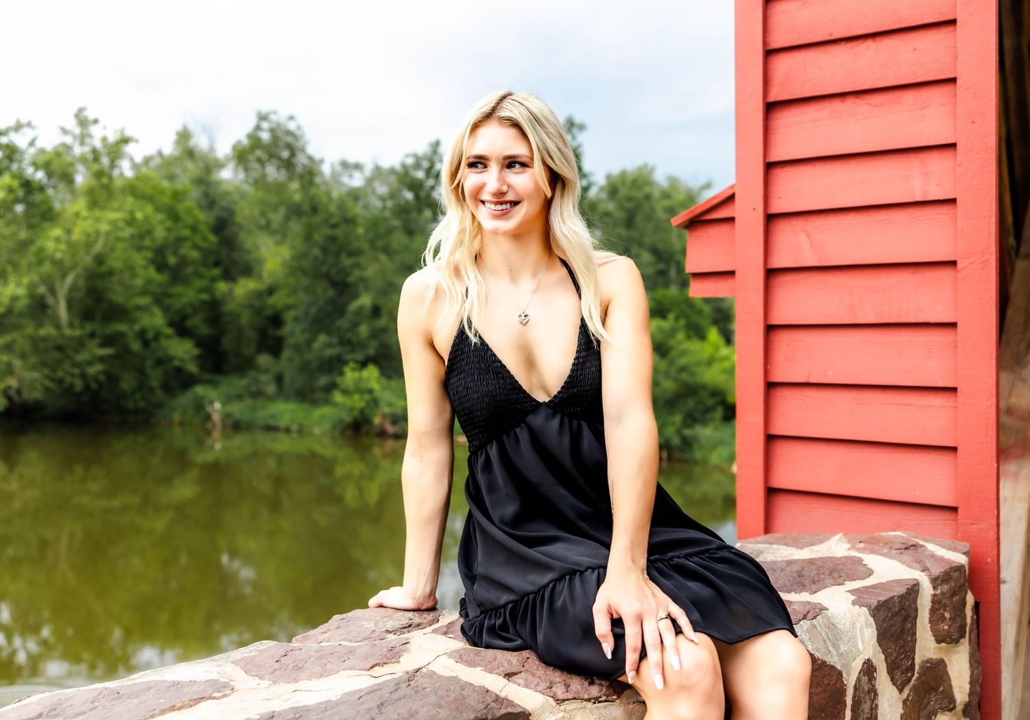 A black summer dress shown against a rustic red building exterior.