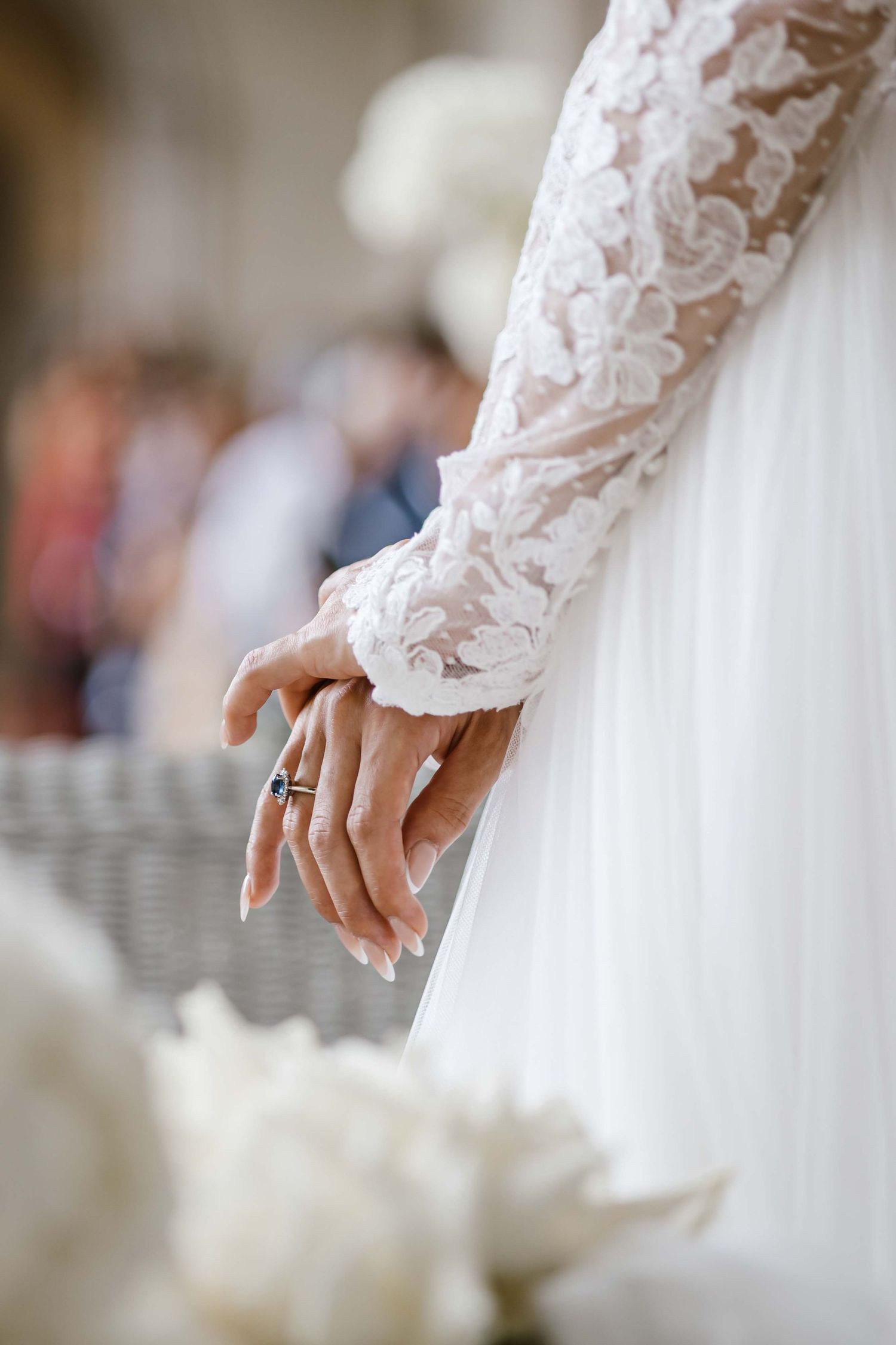 Close-up of bride's hand with wedding ring and lace sleeve detail.