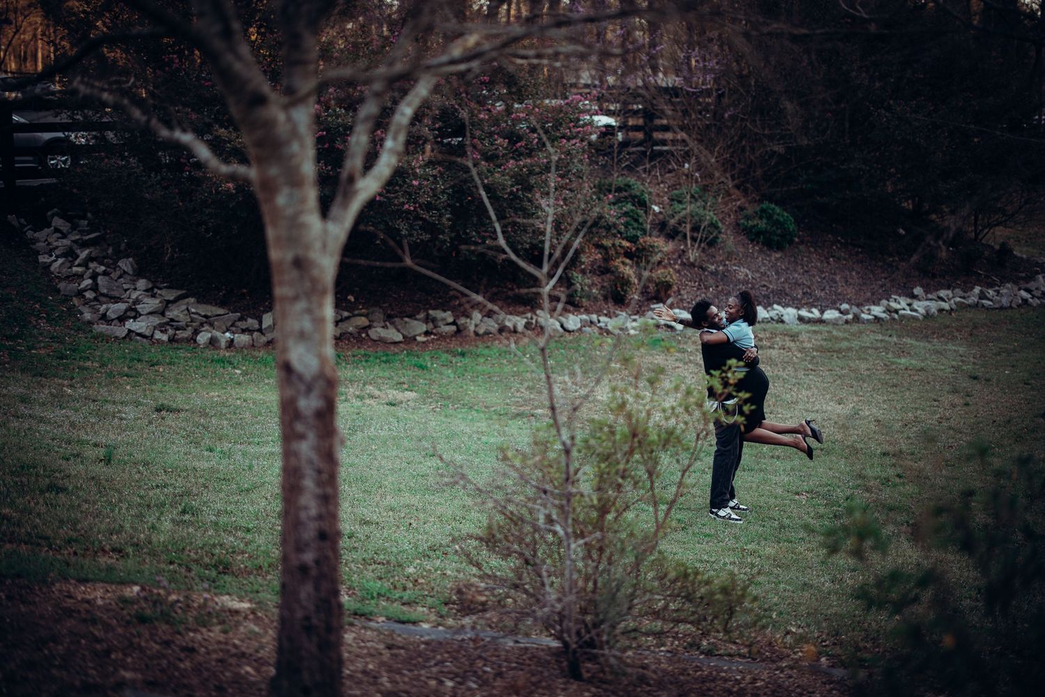 young black man spinning young black woman around playfully in open grass area near marietta, authentic atlanta couples photography