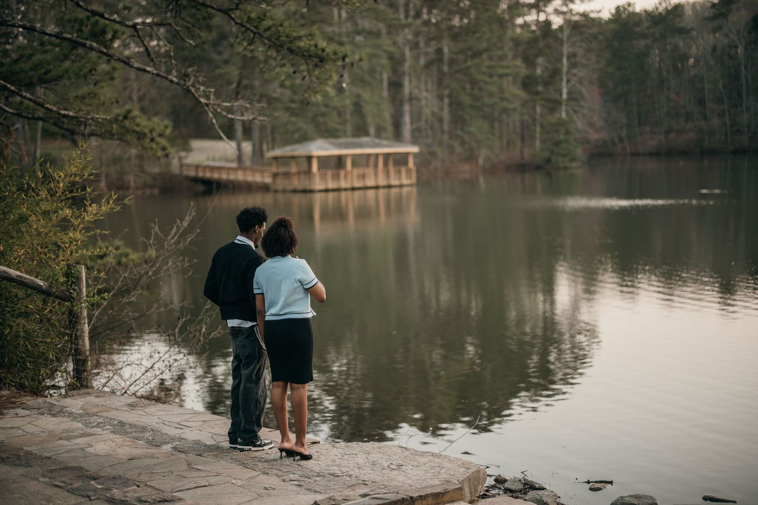 couple standing together by lake's edge, candid engagement photo at atlanta park, marietta couples photographer