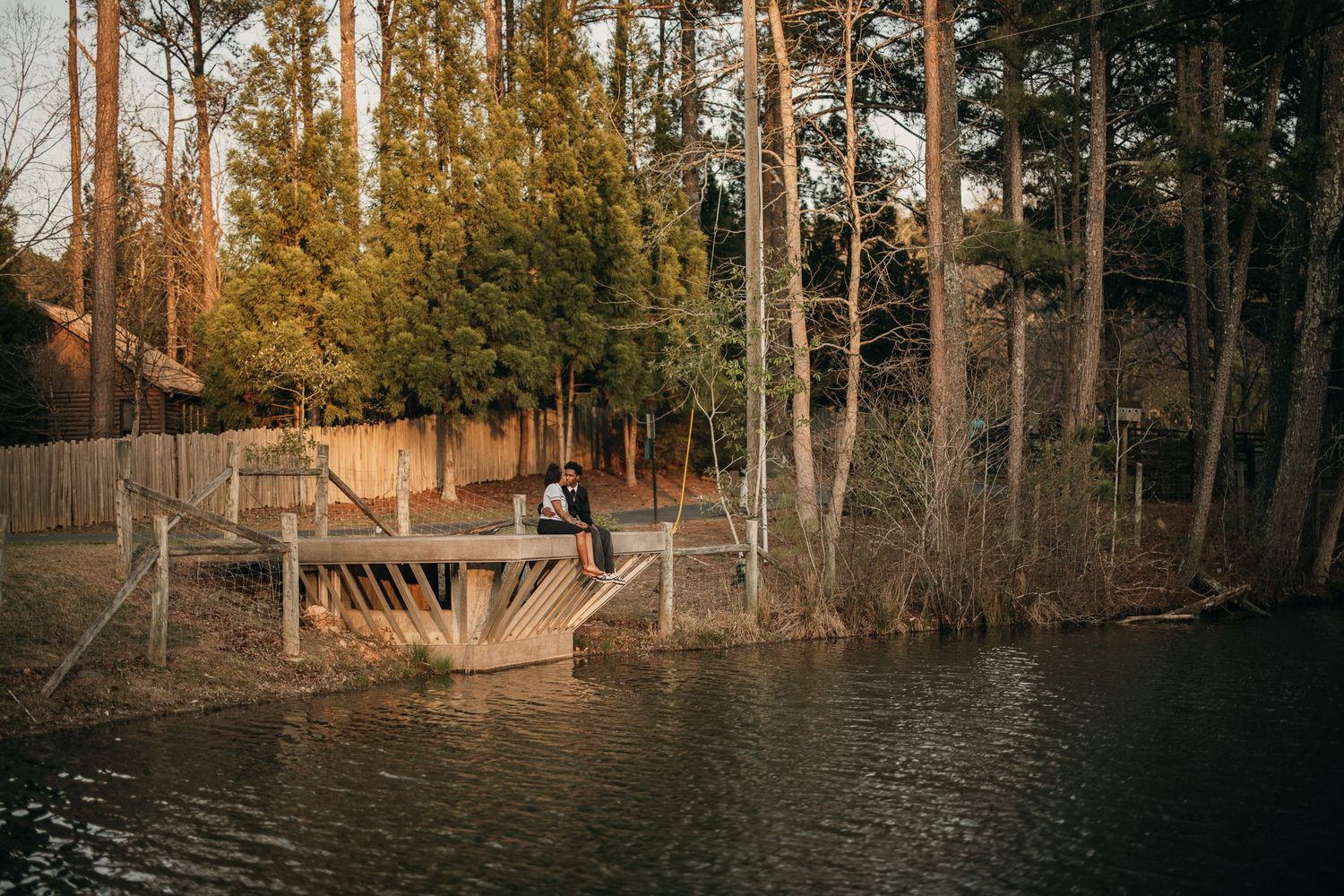 couple sitting together on a dock overlooking small lake in Suwanee, peaceful atlanta engagement session