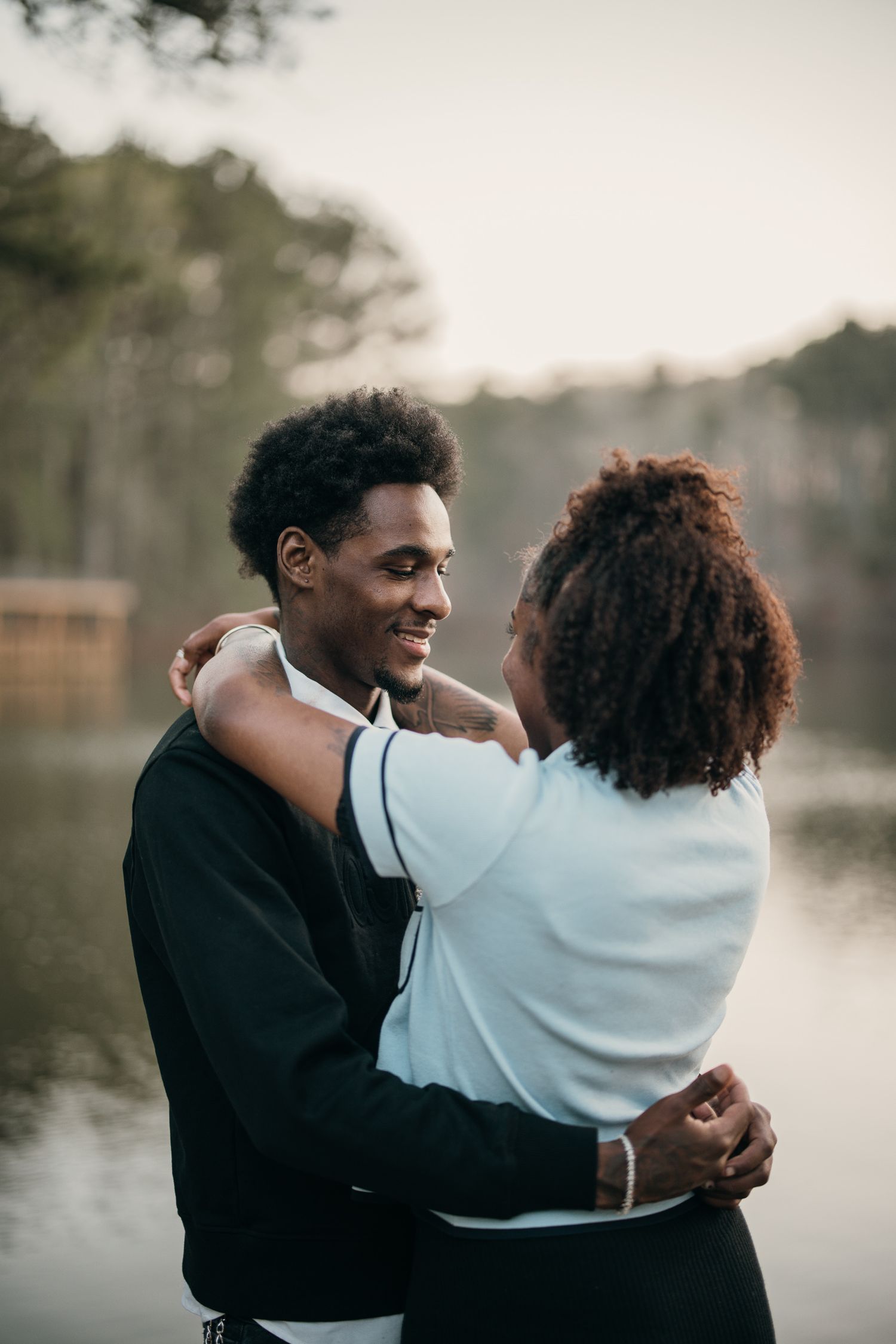 couple embracing with lake in background, Sims Lake Park Suwanee engagement photography candid style, Sims Lake Park couples photography