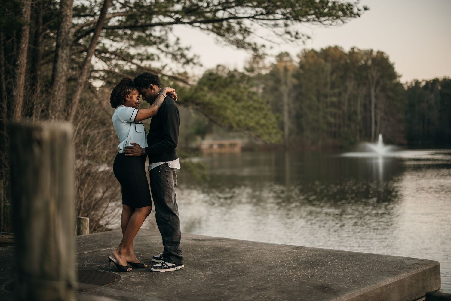 young black couple sharing an intimate moment by the water at sunset - Sims Lake Park Suwanee engagement photography, Sims lake Park couples