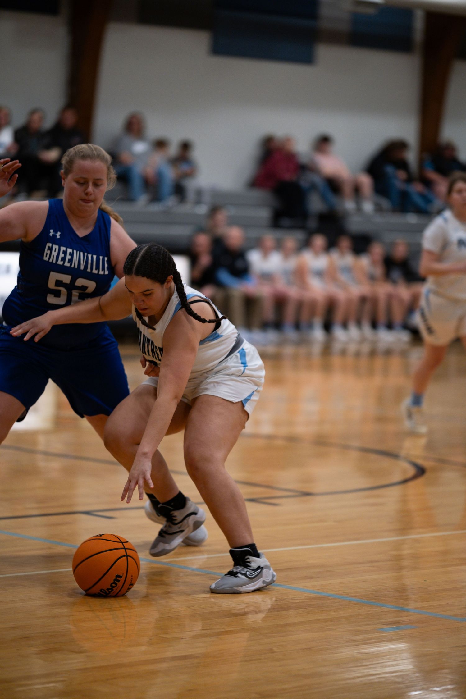 Close-up action shot of basketball players diving for a loose ball during an intense game on wooden court.