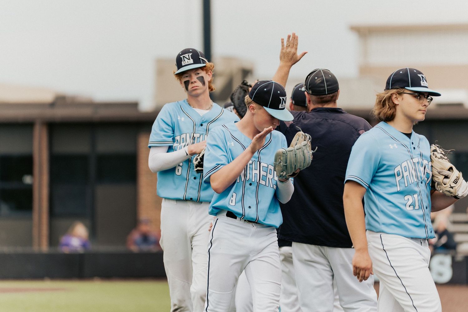Baseball team members celebrating victory with high fives and cheers.