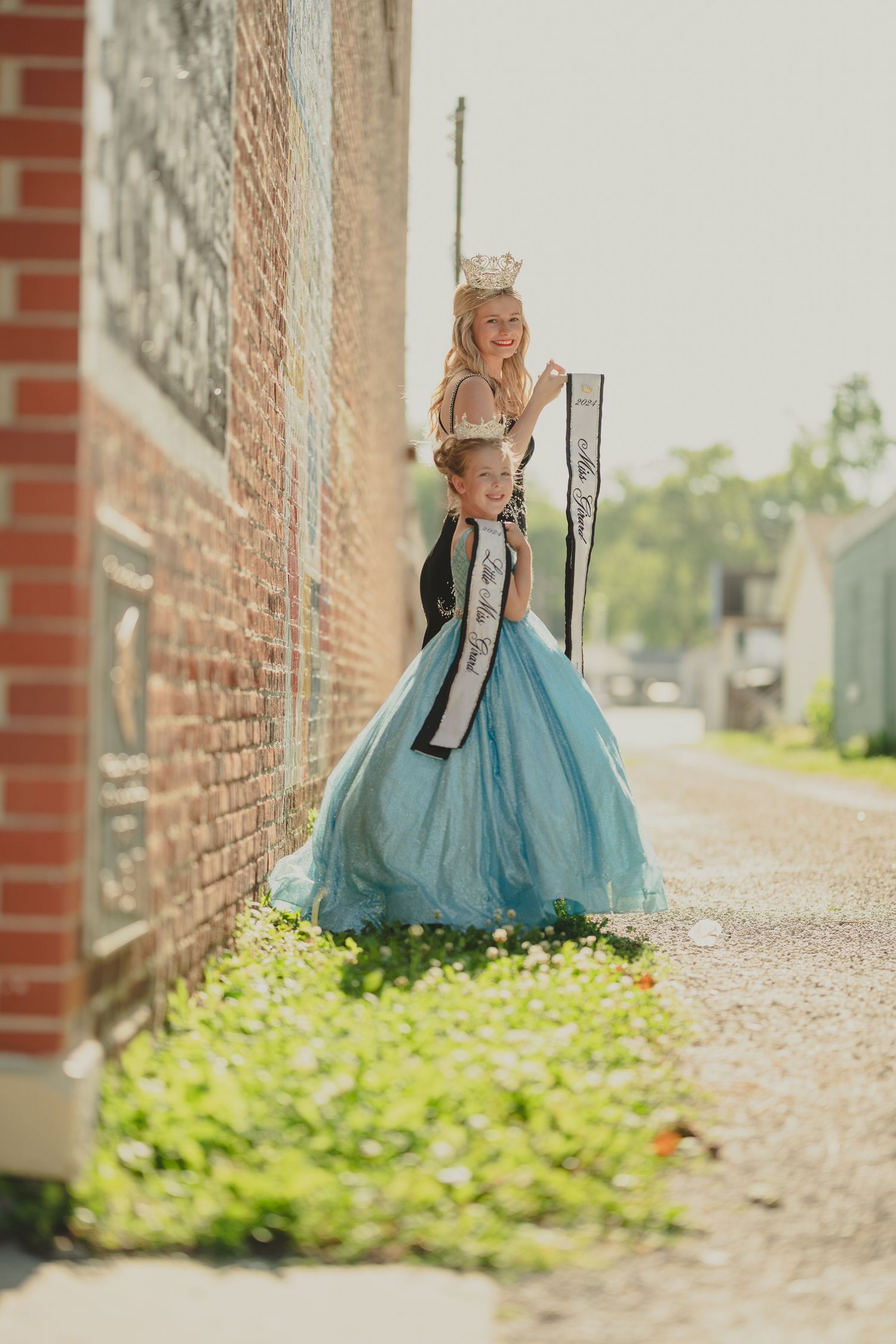 Blue ballgown dress against brick wall backdrop in downtown setting.
