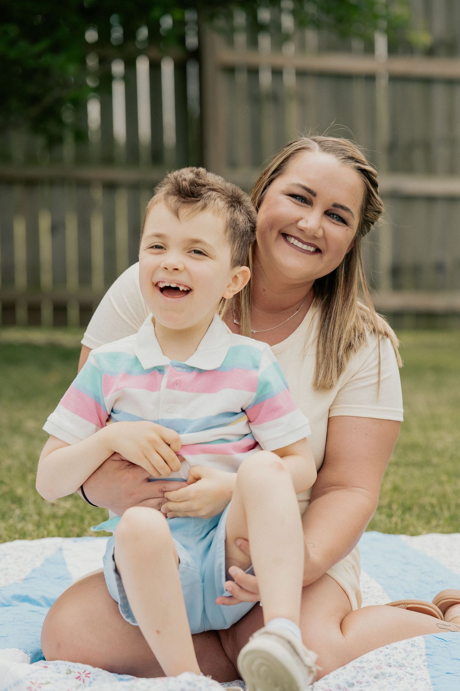 Mother and child sharing joyful moment together on picnic blanket outdoors.