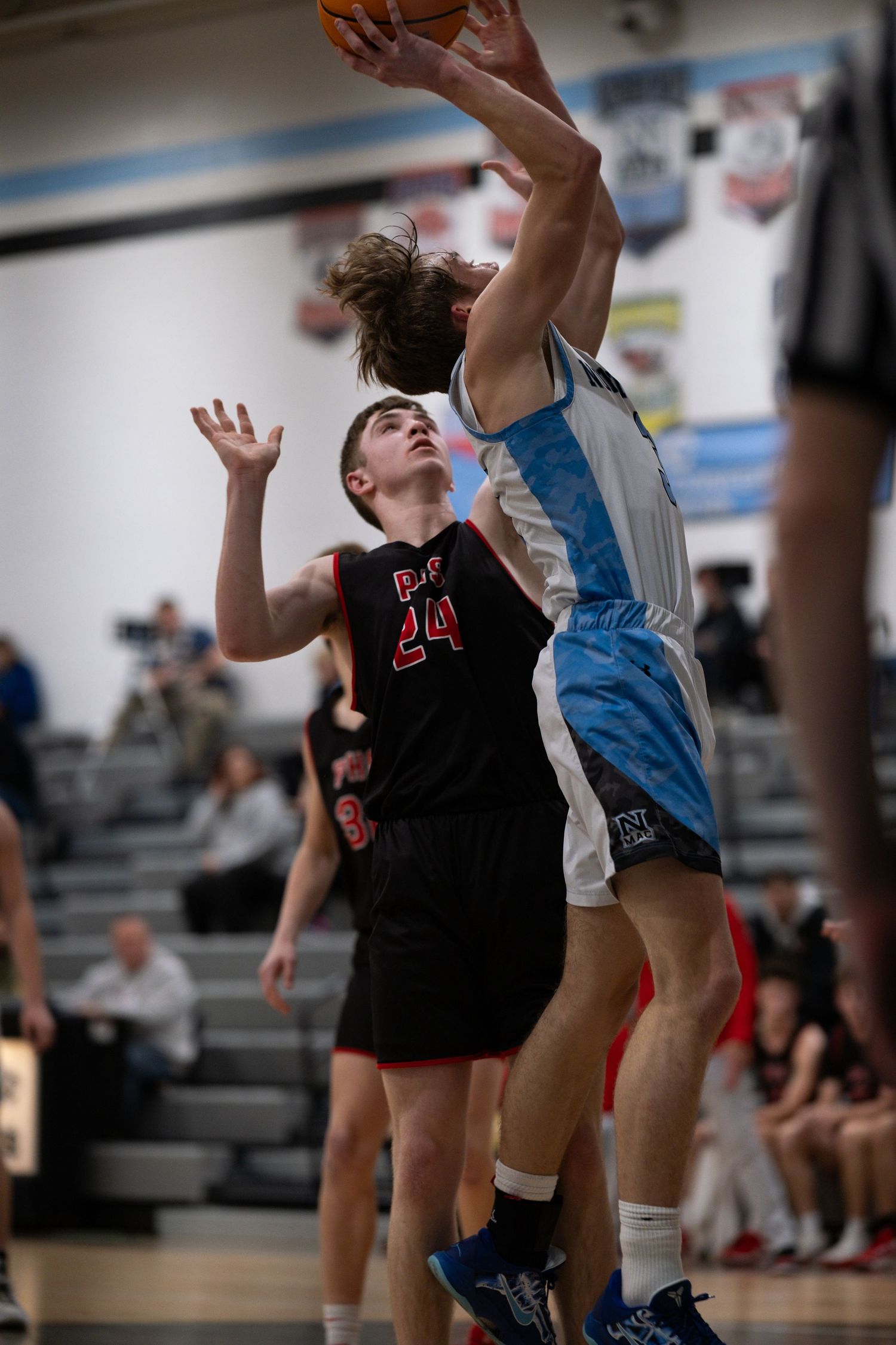 Two basketball players compete for a rebound during an intense game.
