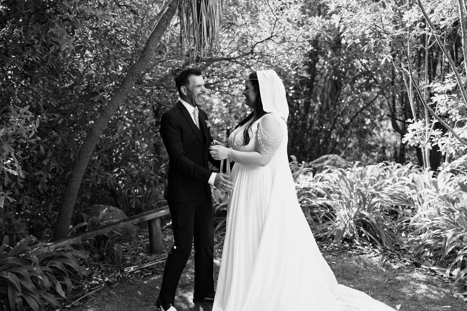 An intimate wedding ceremony moment captured in black and white among garden foliage.
