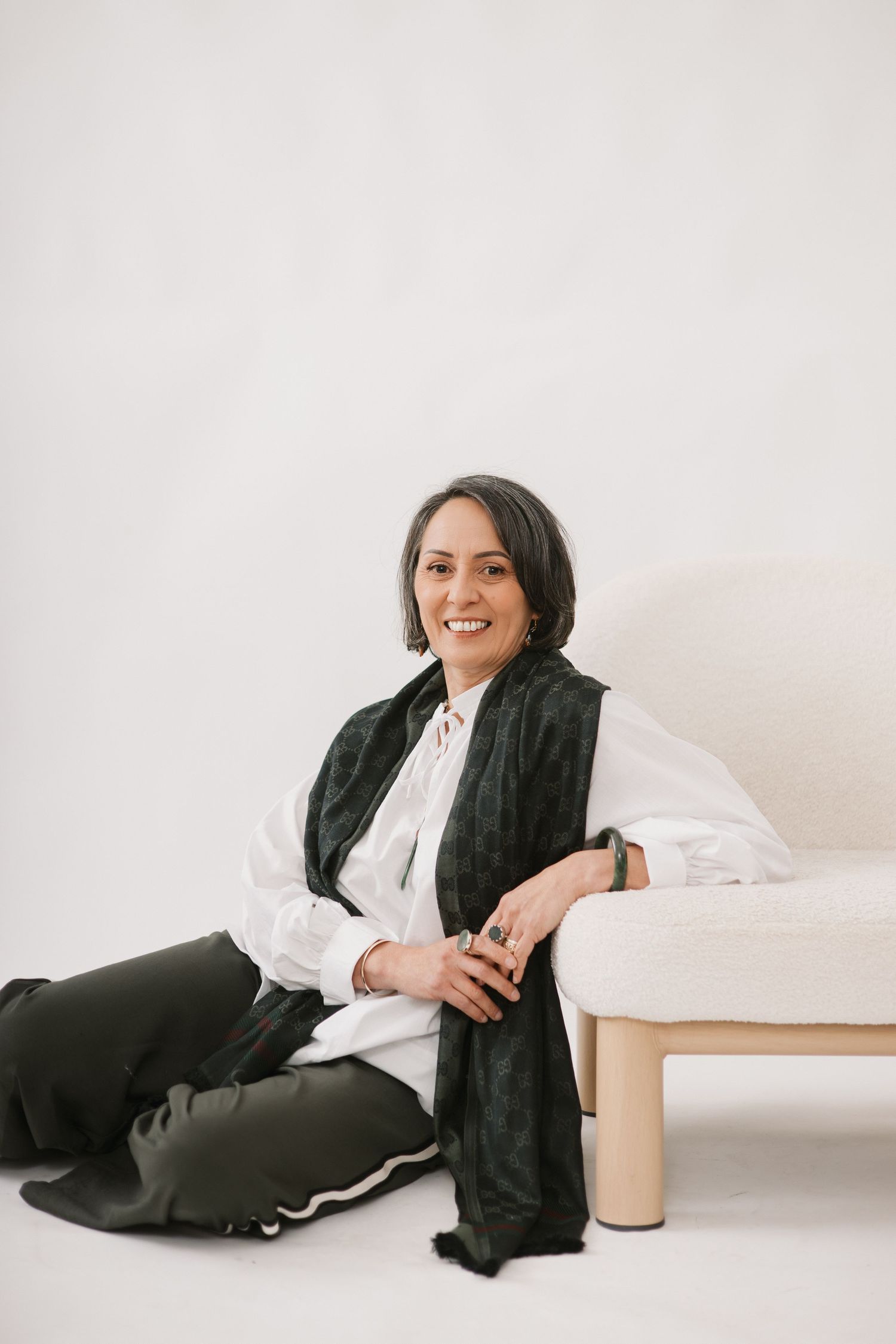 A person wearing black and white casual attire relaxes in different reclining poses on a white couch against a light background.