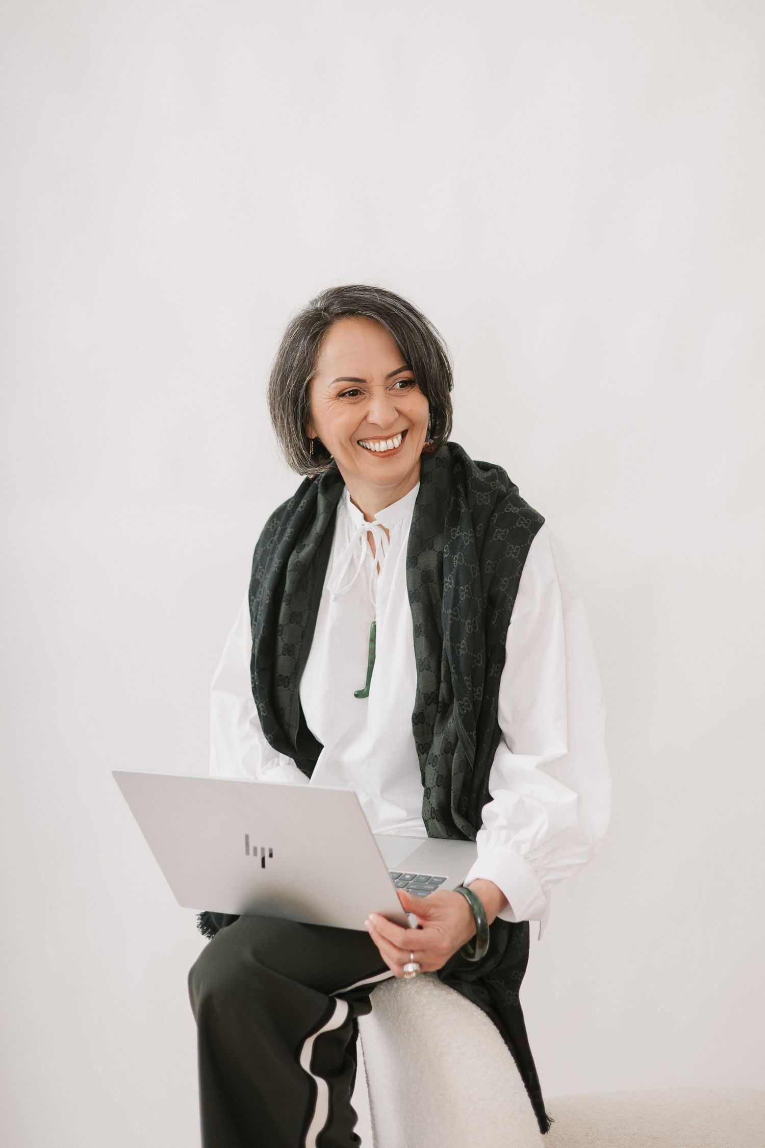 Business casual portrait with white blouse and dark scarf while holding digital tablet against light background.
