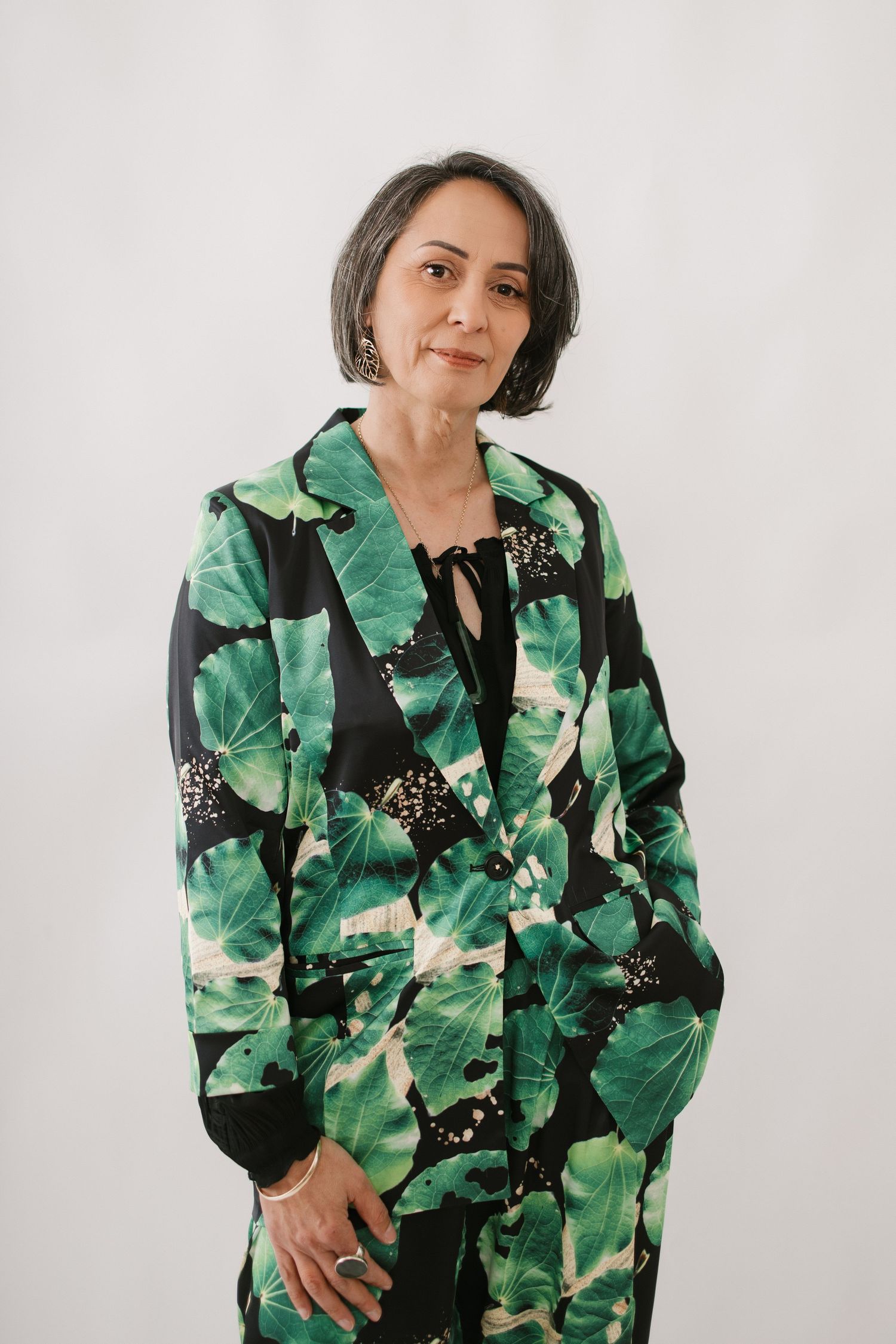 Fashion portrait featuring bold green tropical print jacket against white studio background.