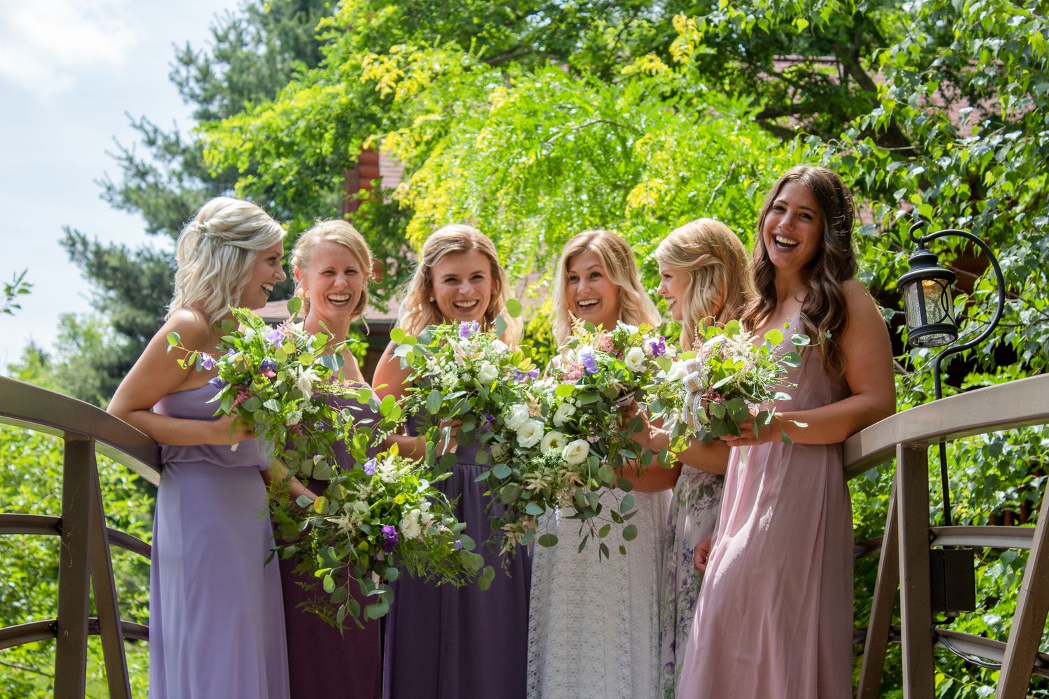 Wedding party celebrating outdoors with colorful floral arrangements and greenery.