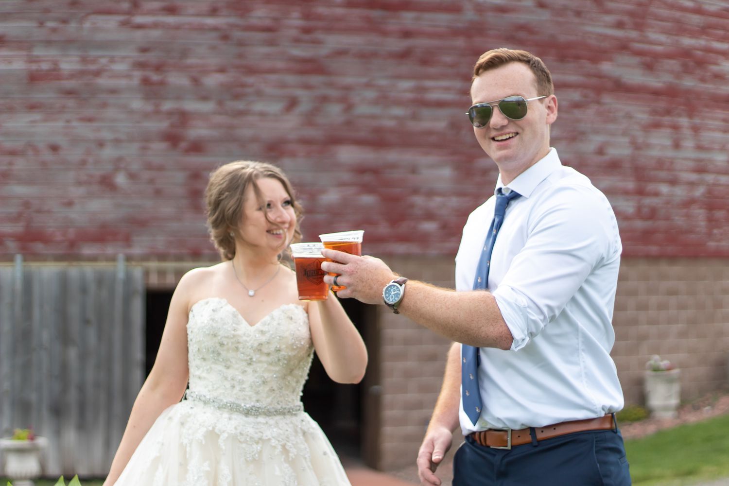 A wedding celebration moment with drinks against a rustic red barn backdrop.