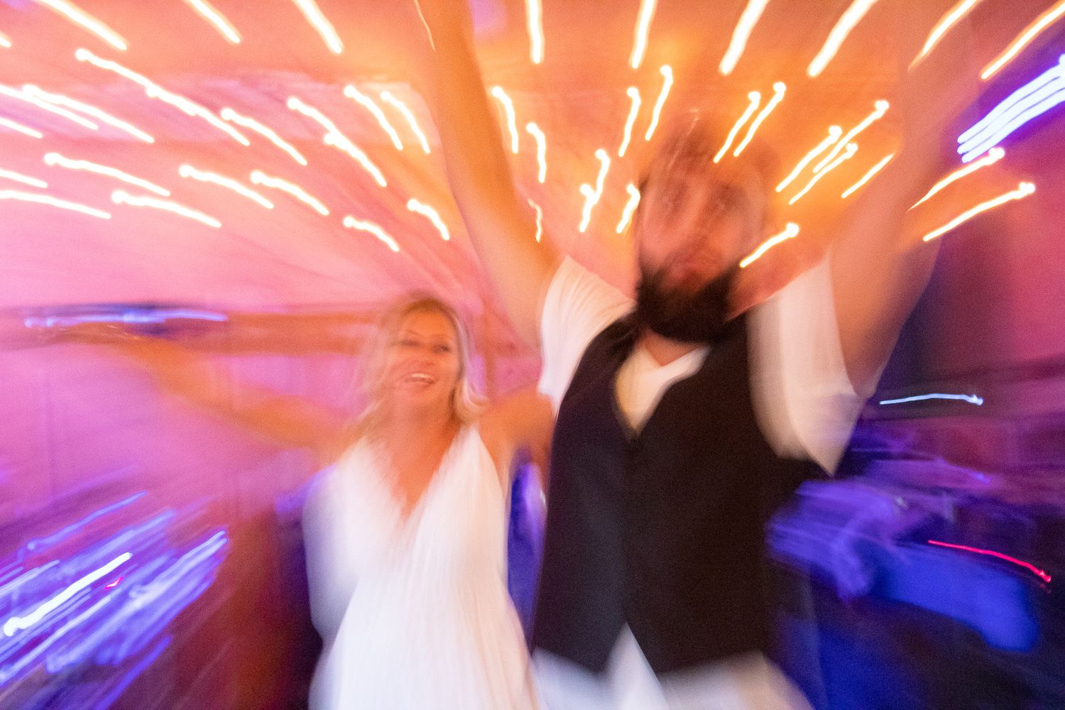 Motion-blurred dance floor scene with colorful lights creating streaks across the image.