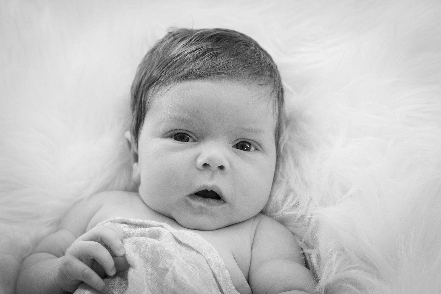 Close-up black and white portrait of baby on white background.