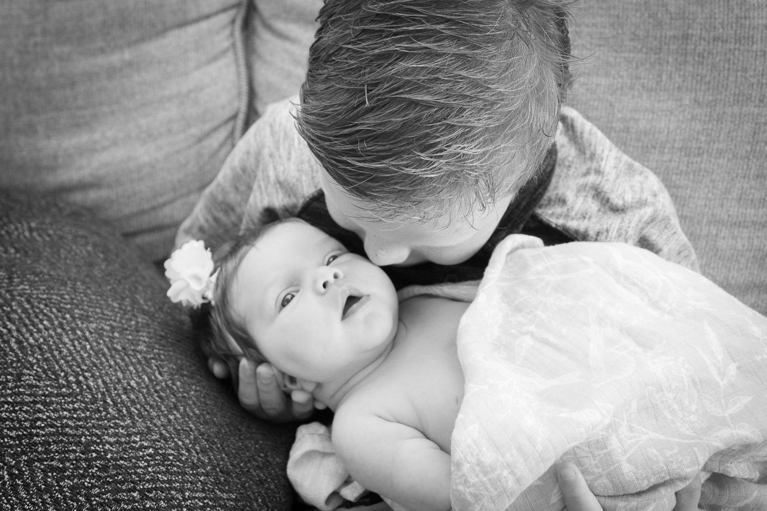 Black and white tender moment between parent and baby on couch.