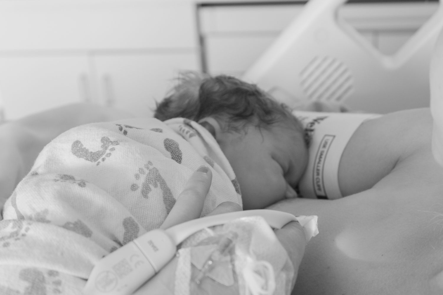Monochrome capture of newborn sleeping peacefully in hospital bed.