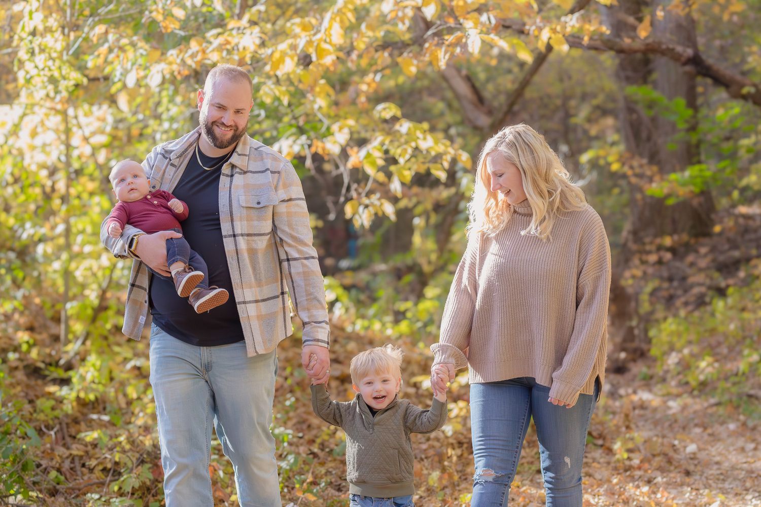 Family enjoying a walk together in a golden autumn forest during sunset.