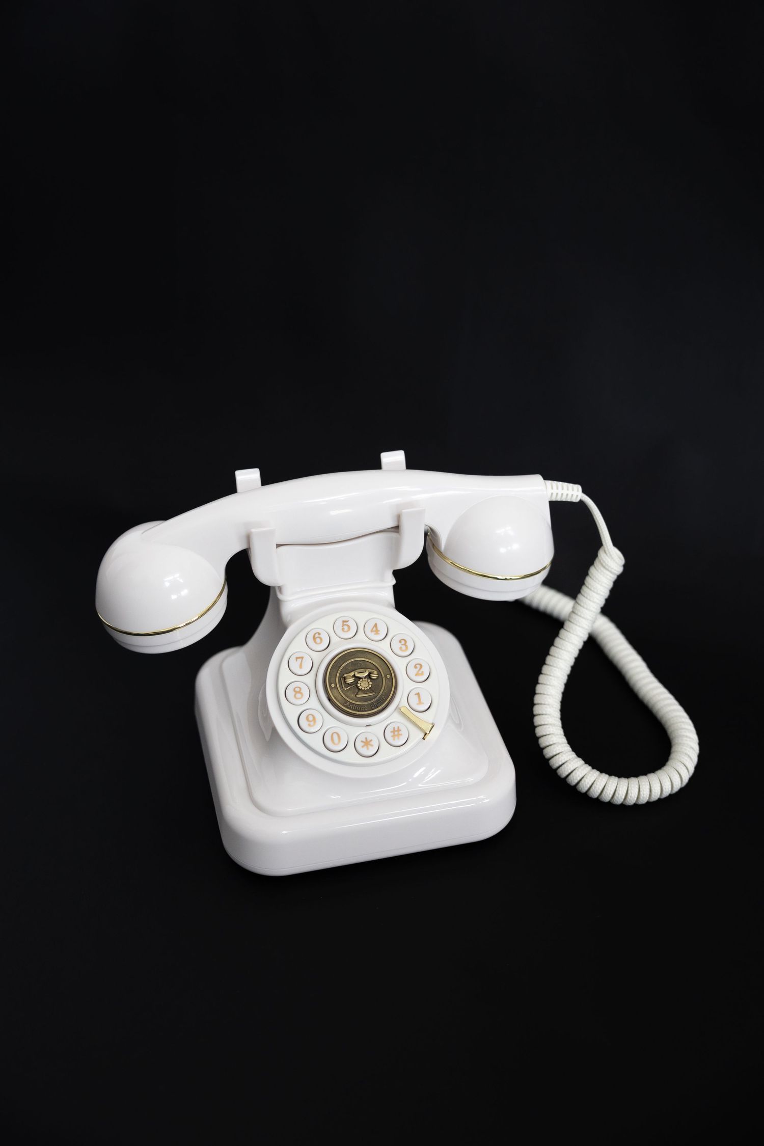 A vintage white rotary telephone hangs at different angles against a black background in a triptych composition.