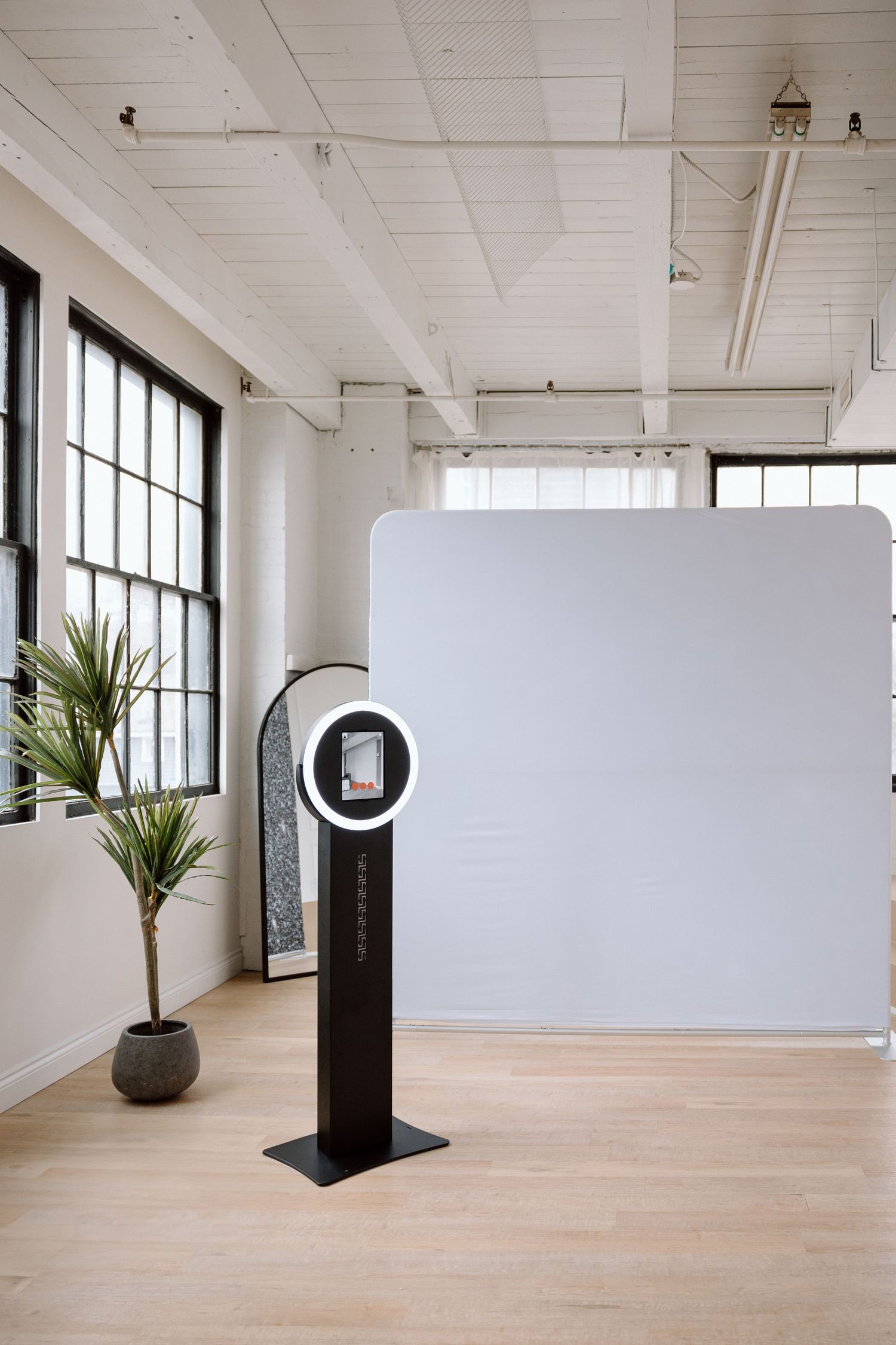 Modern photo booth setup with white backdrop and digital kiosk in bright studio space.