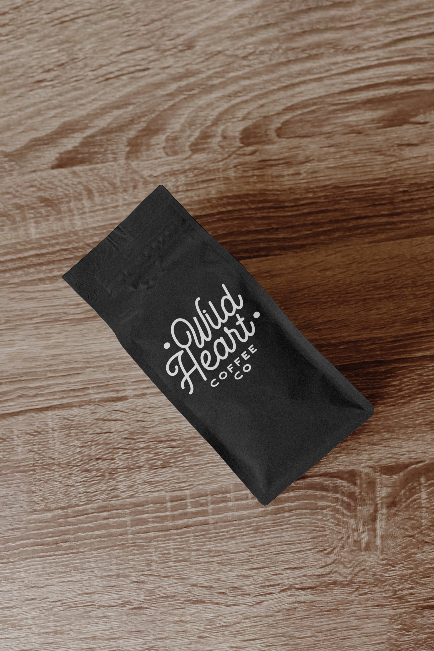 Black business cards with handwritten white text displayed on wooden surface showing elegant branding design.