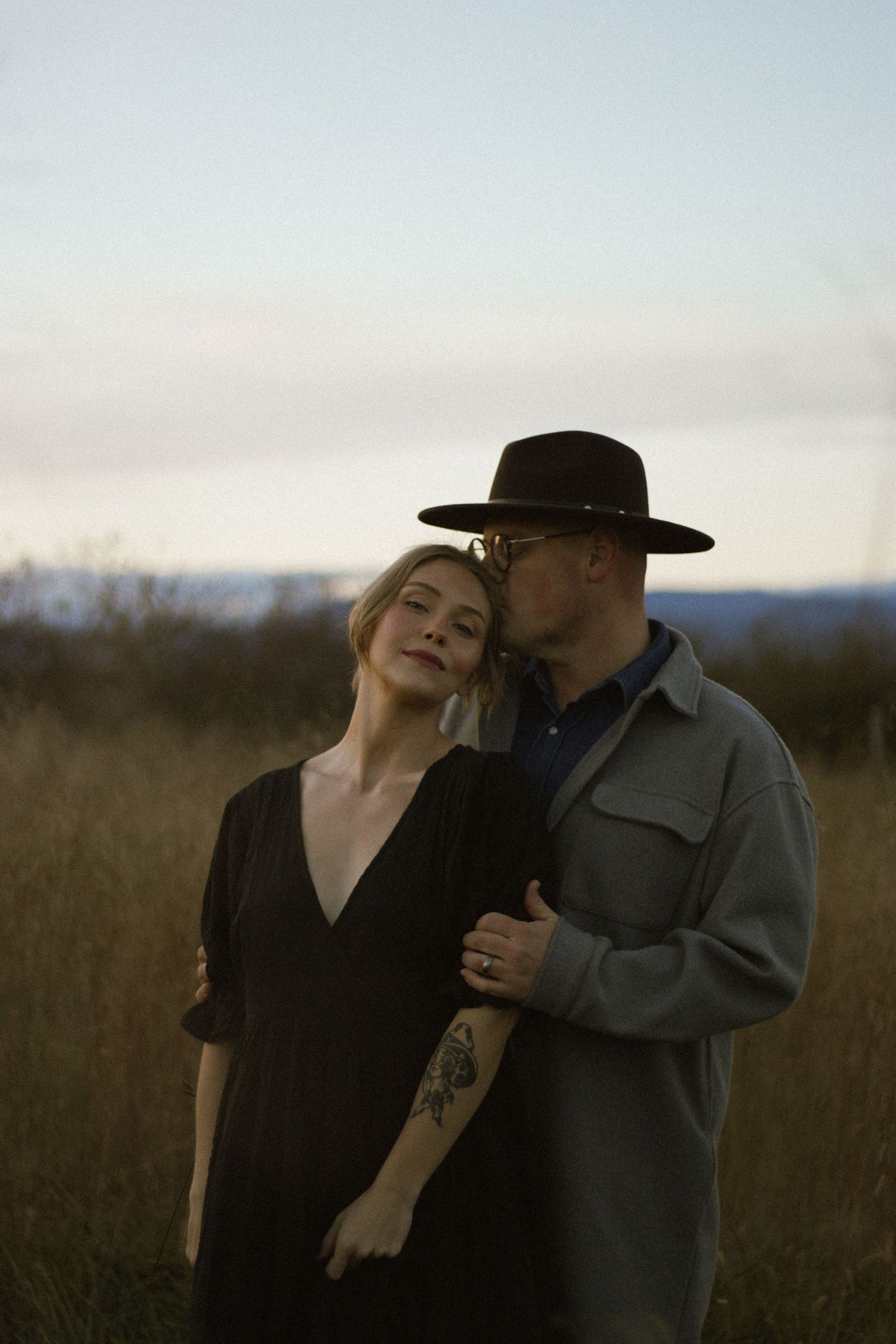 Artistic outdoor portrait in field at sunset showcasing intimate moment.