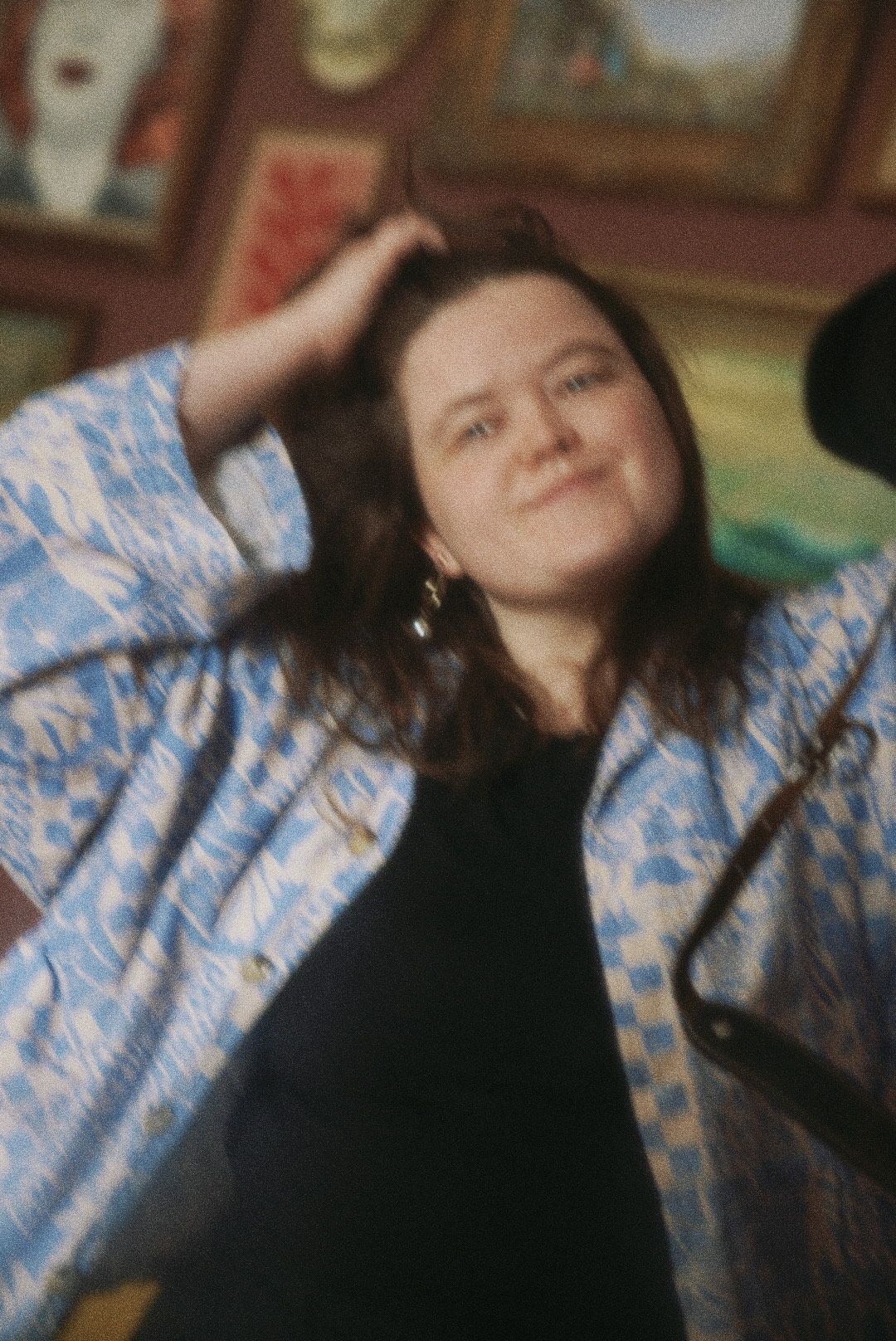 A person in a floral patterned shirt leans back with windswept hair in a casual indoor setting.