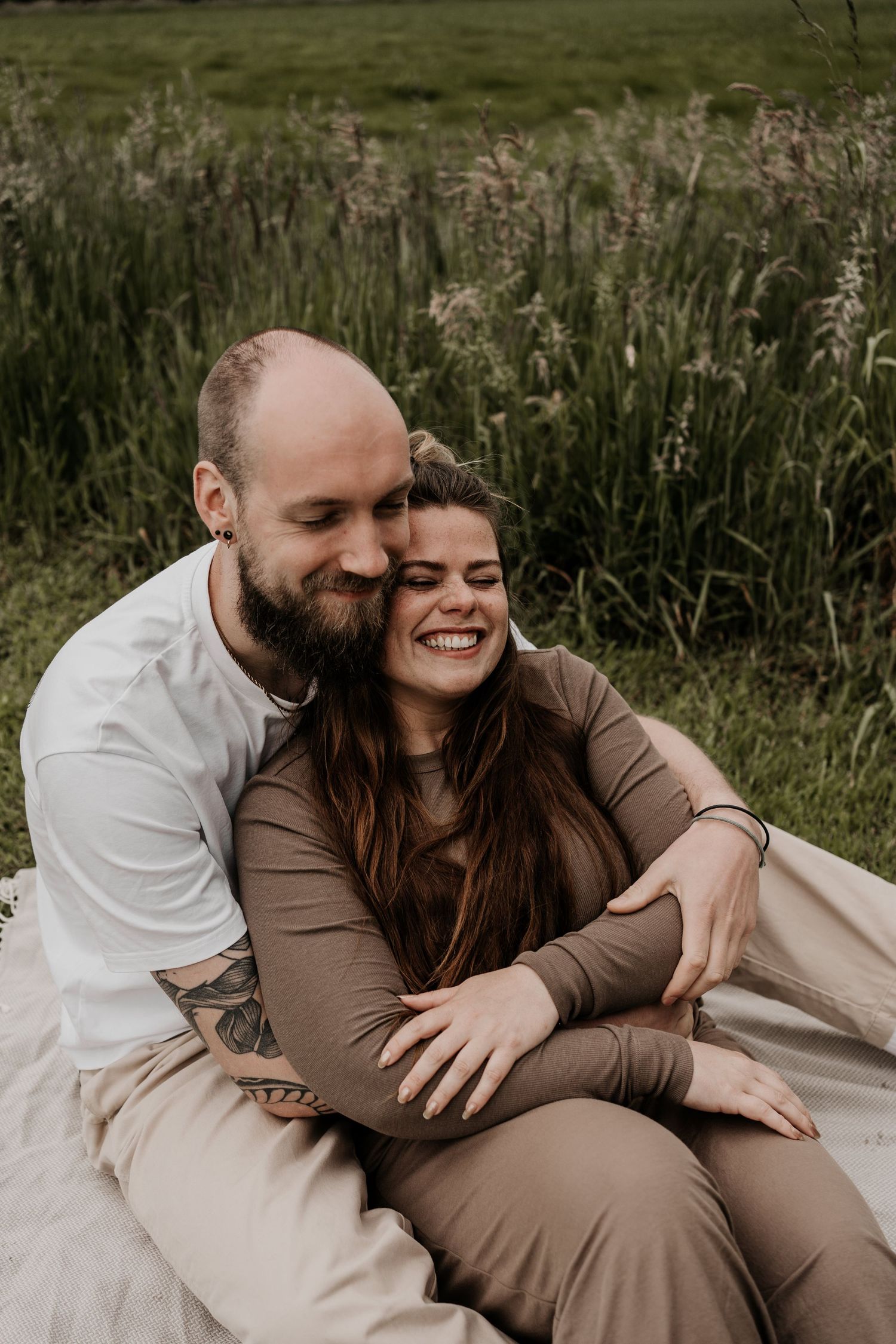 koppel tijdens een loveshoot in elkaars armen terwijl ze verliefd lachen