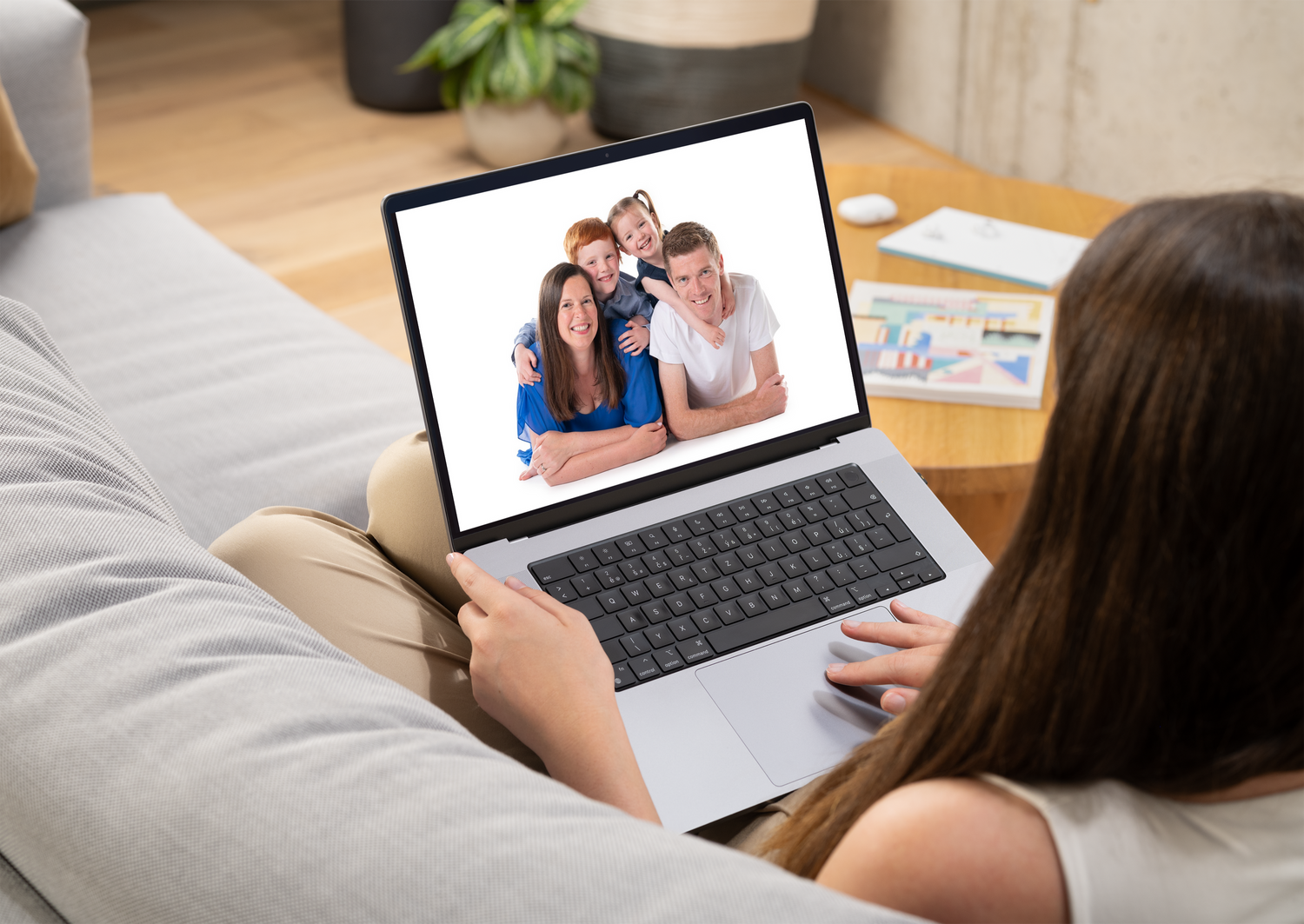 Person using laptop while relaxing on couch for virtual meeting.