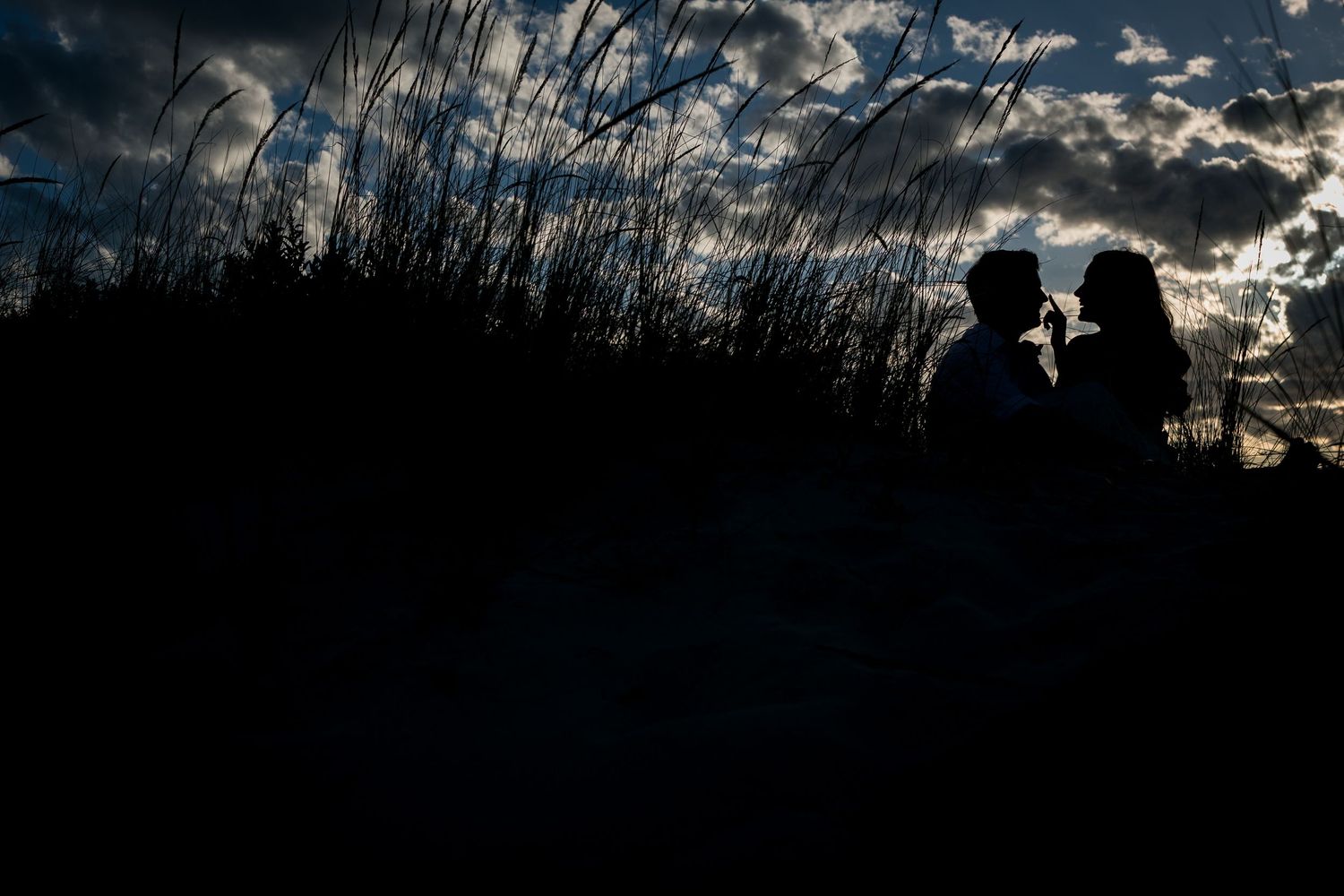 Engaged couple smiling and holding hands during their engagement photo session at leighton beach celebrating their love with silhouette