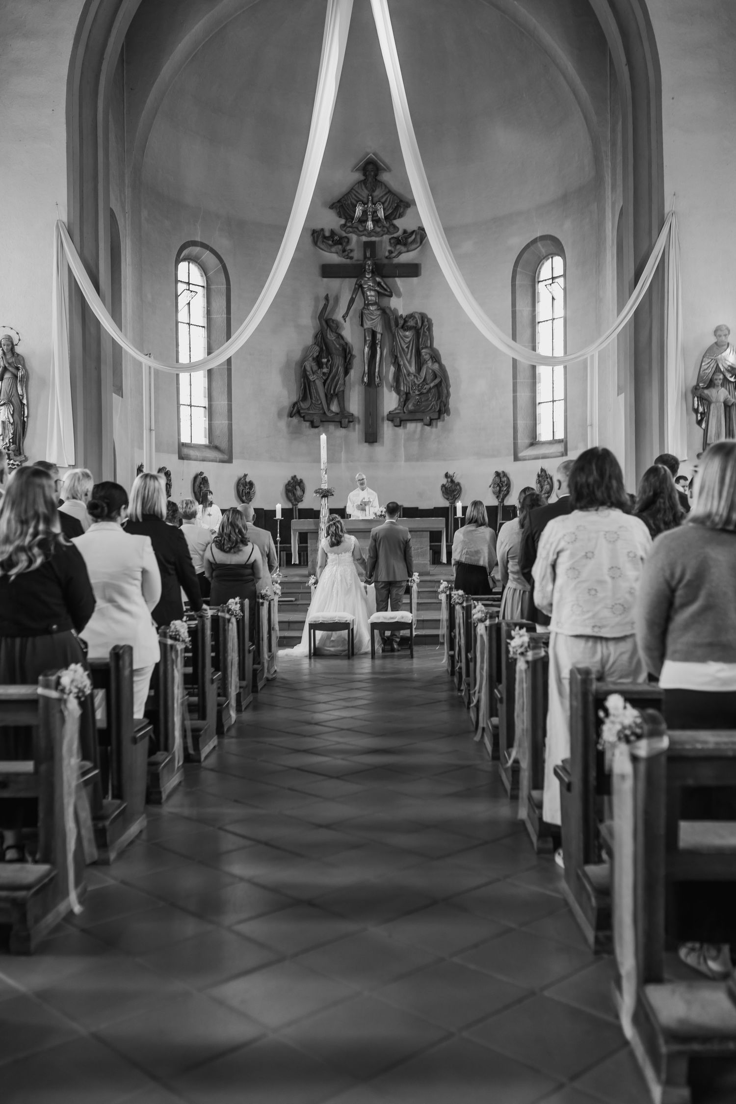 Black and white photograph of a church wedding ceremony with guests seated in wooden pews.
