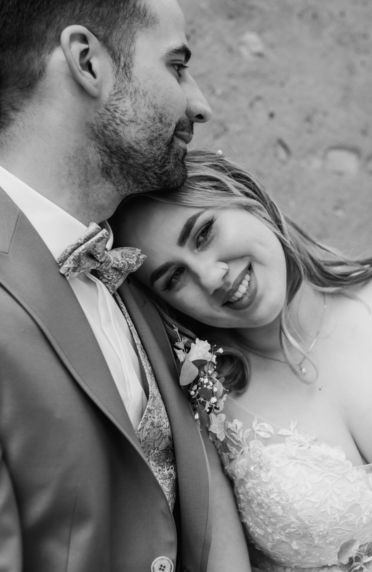 Intimate black and white portrait of newlyweds sharing a tender moment with the bride smiling against the groom's shoulder.
