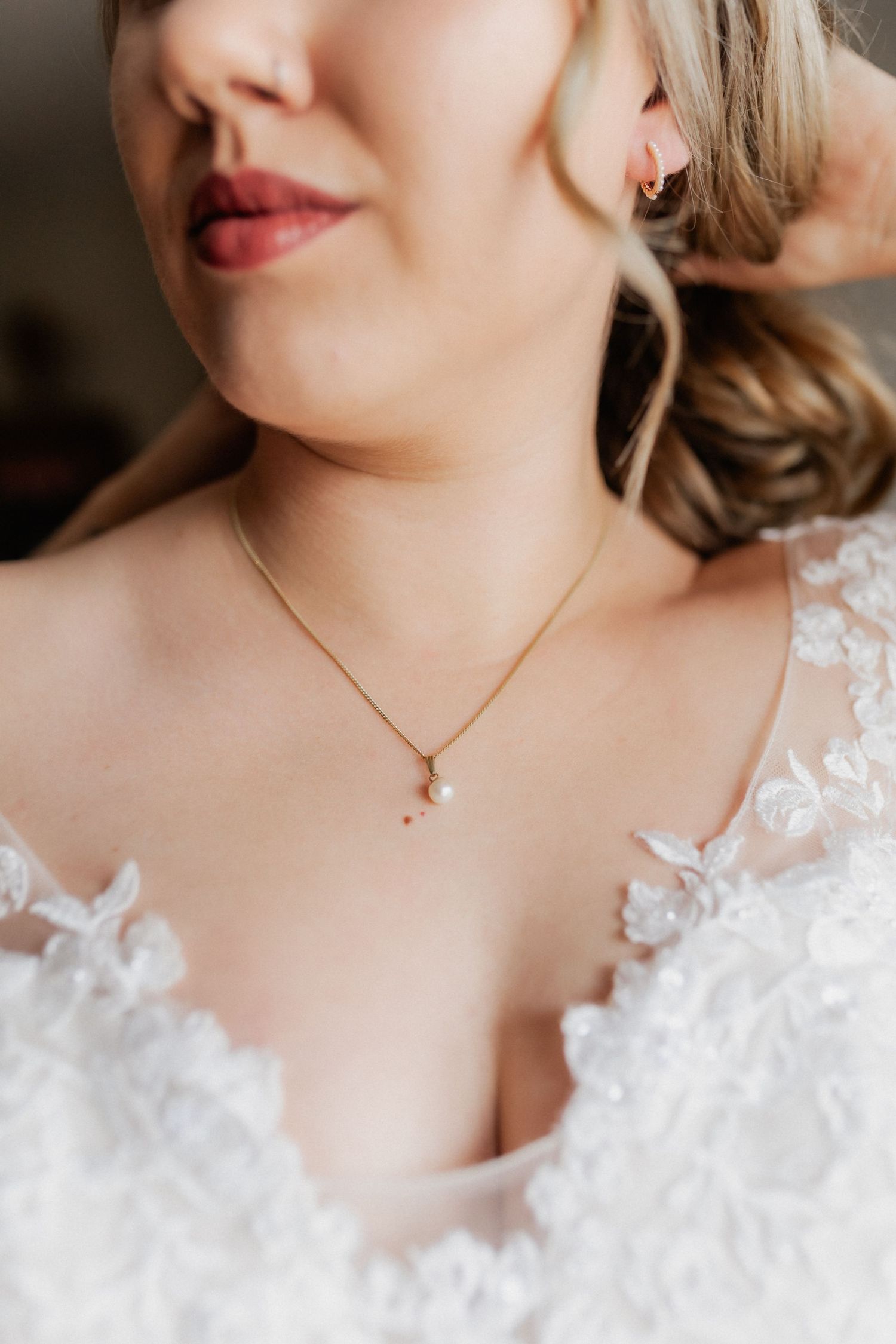 Delicate bridal jewelry and lace details on wedding dress neckline.