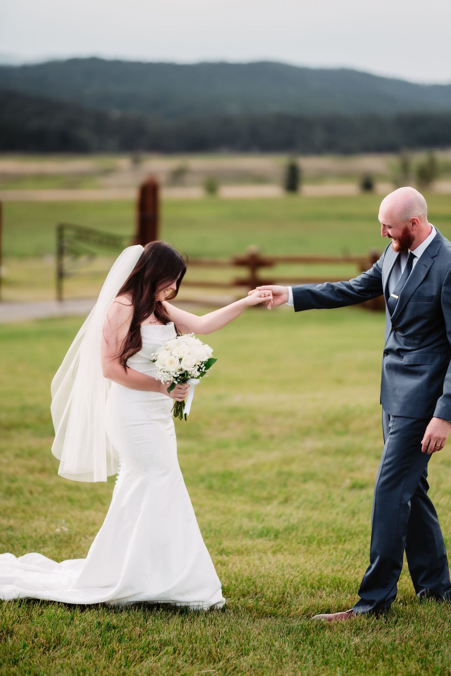 A joyful wedding dance moment captured in a mountain field with rolling hills in the background.