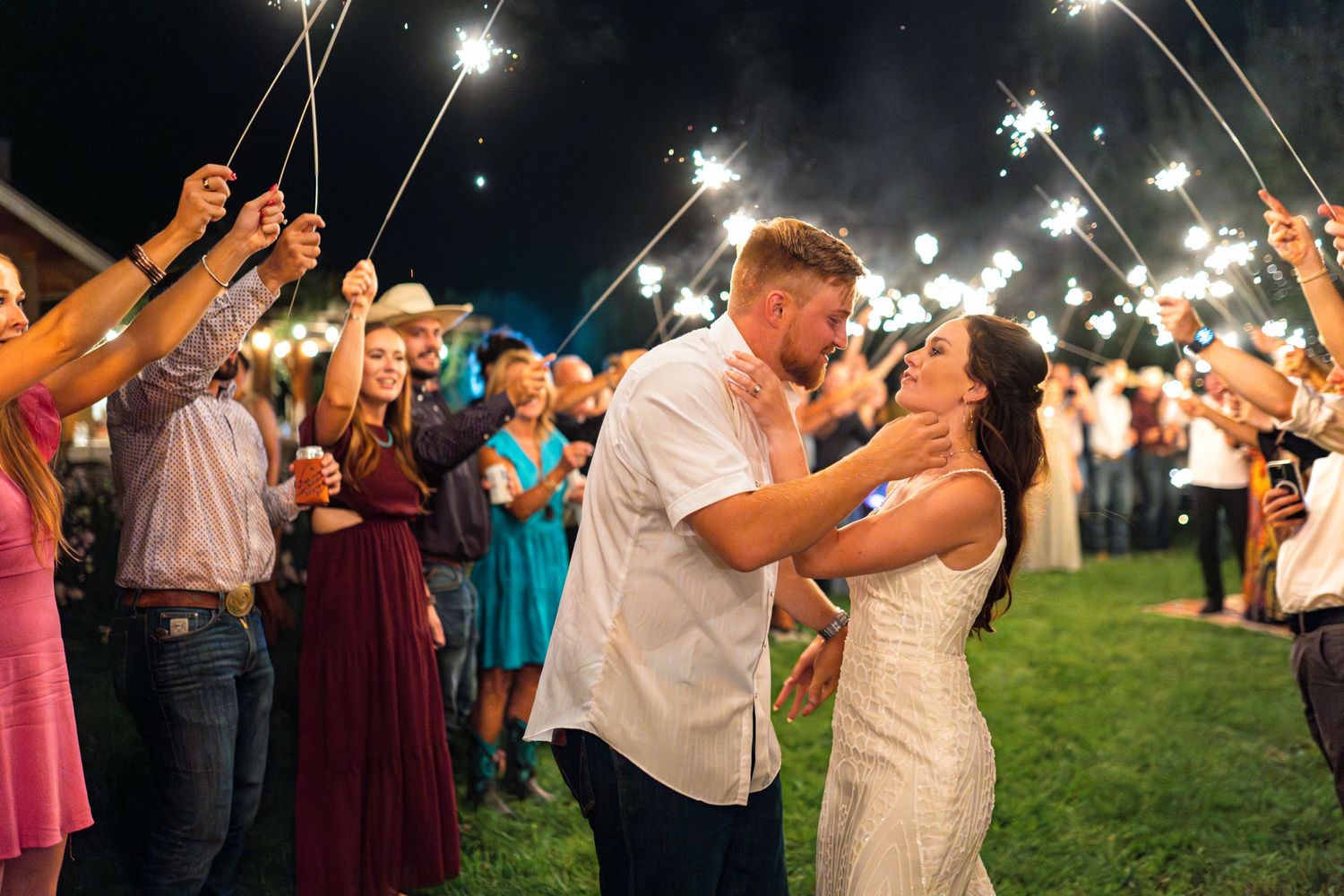 Newlyweds share a romantic moment during their sparkler exit surrounded by celebrating guests.