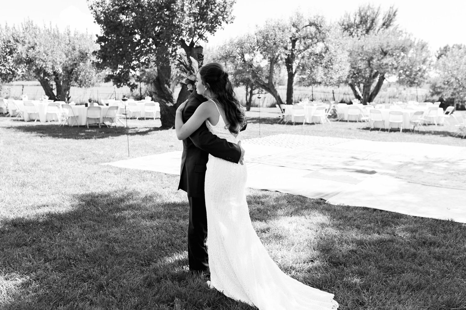 A tender black and white portrait of newlyweds embracing in an outdoor garden setting.