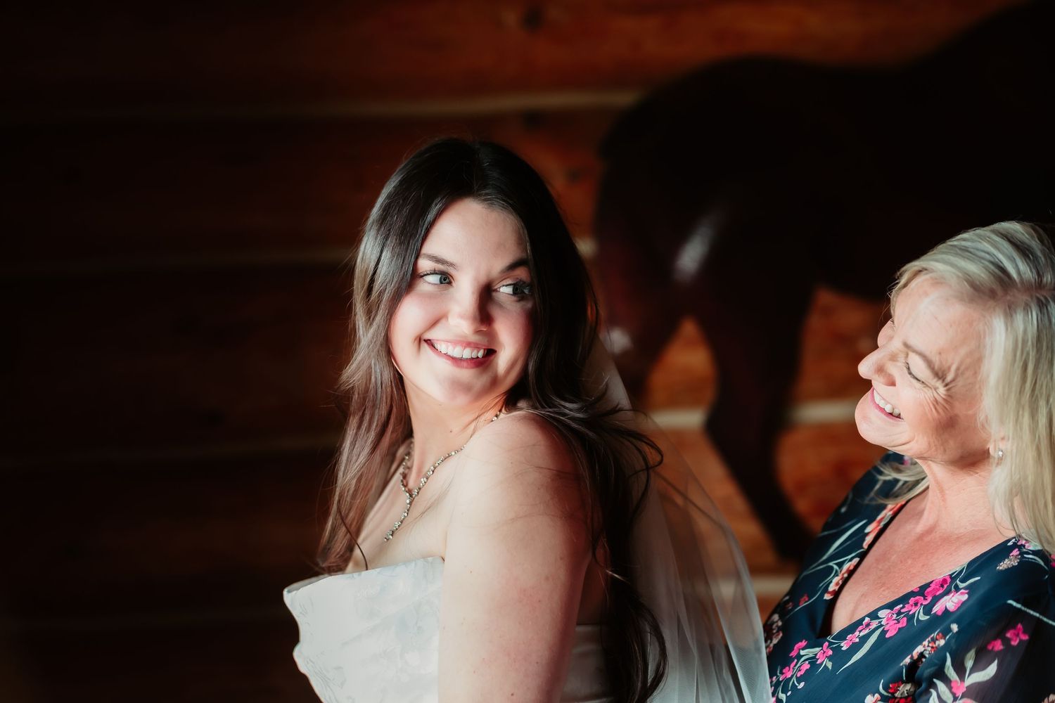 Two women share a joyful moment together at a rustic indoor venue with warm lighting.