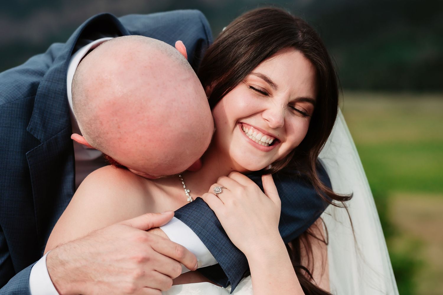 An intimate embracing wedding couple sharing a candid moment outdoors.